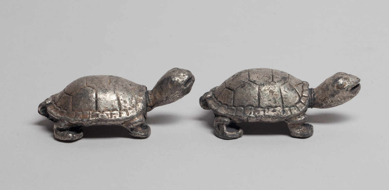 Two Japanese Metal Toggles: Two Japanese metal cast pieces of turtle form, the underside carved with inscription. Approx. 2.57*1.47*0.85 inch (larger). The Estate of the Store Closed Sale in DTLA.