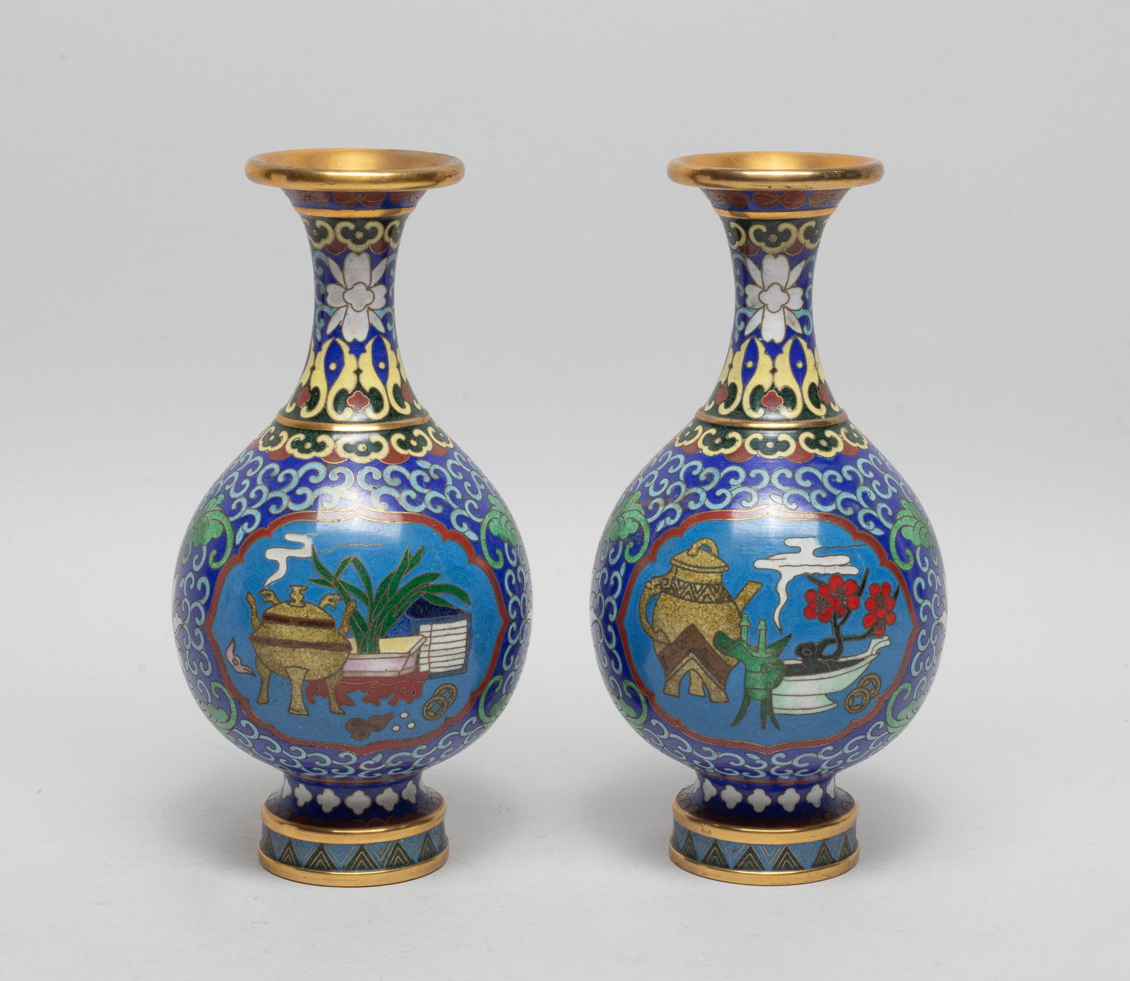 Two Chinese Cloisonne Cabinet Vases: Each of pear shape rising from a splayed foot to a waisted neck with a flared rim, enameled with two ruyi-head shaped medallions of scholar bogu pattern, against deep blue background suffused with lot