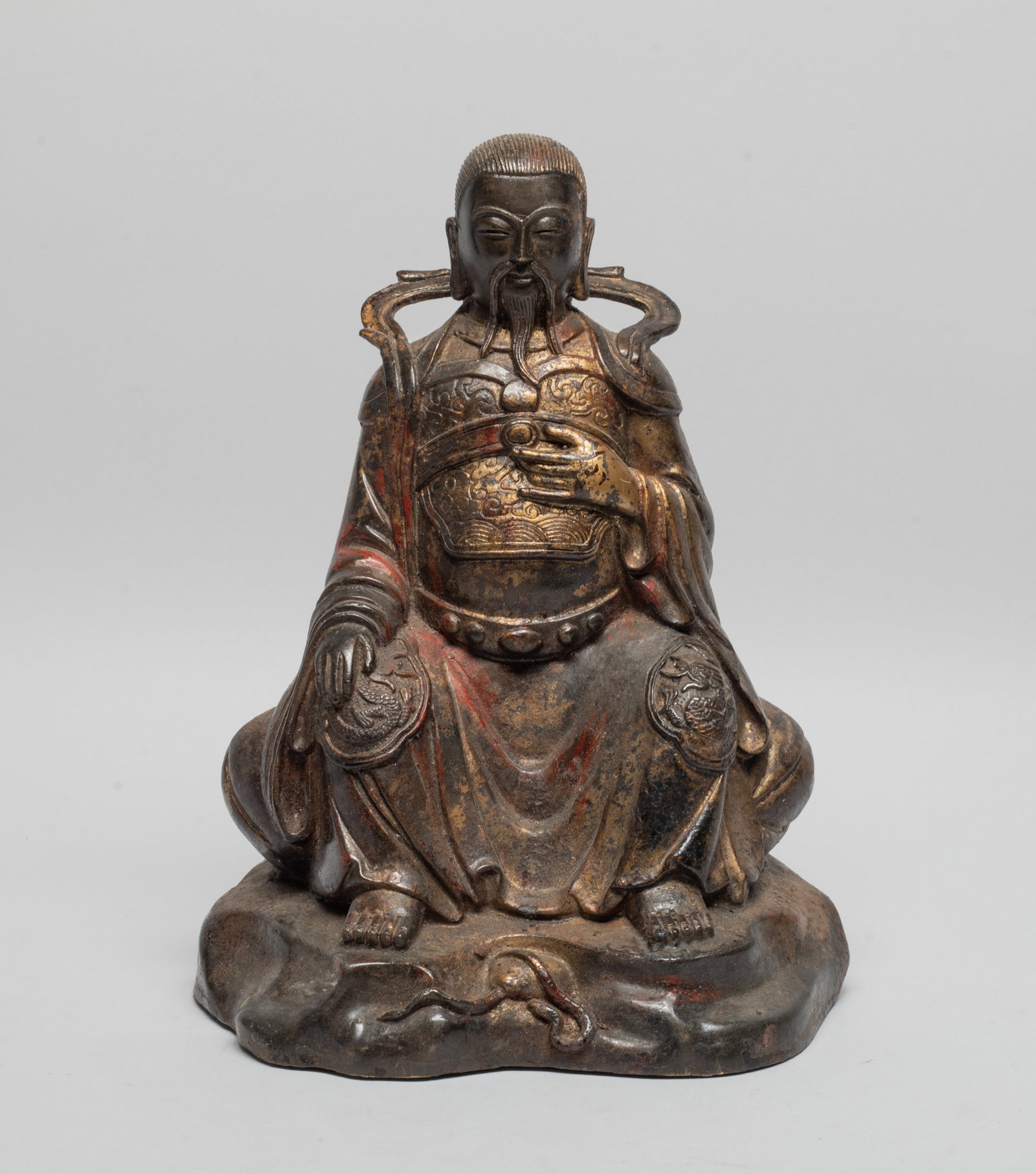 Chinese Painted Bronze Sculpture of Buddha: The painted bronze Buddha cast in seated position, wearing a long flowing robe, the chest carved with clouds and waves, the knees carved with dragons. Approx. 9.5*7.2*5.4 inch.
