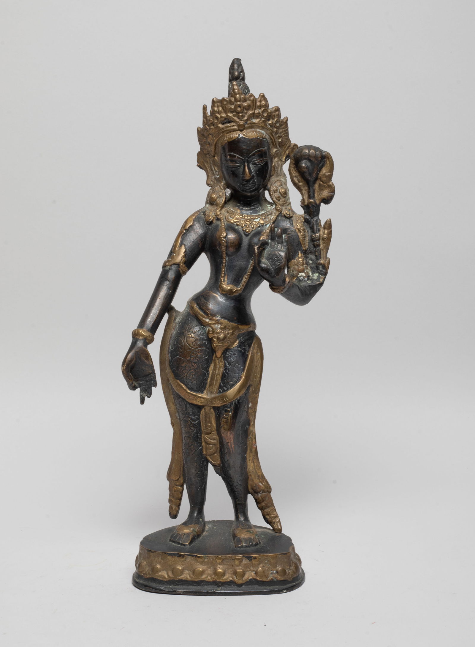 Tall Nepal Bronze Buddha: The Buddha cast standing with his hands in vitarkamudra, draped in scarf and beaded jewelry, his face with meditative expression flanked by an elaborate diadema, his hair urmounted by Buddha form ushn