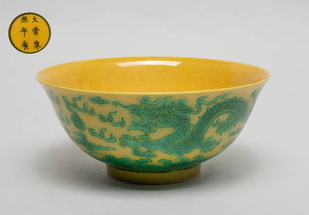 Chinese Export Porcelain Dragon Bowl: The bowl overall yellow glazed, the exterior carved in low relief and painted in green color with two dragons pursuing flaming pearls amidst flames and clouds above waves, the bottom marked with six c