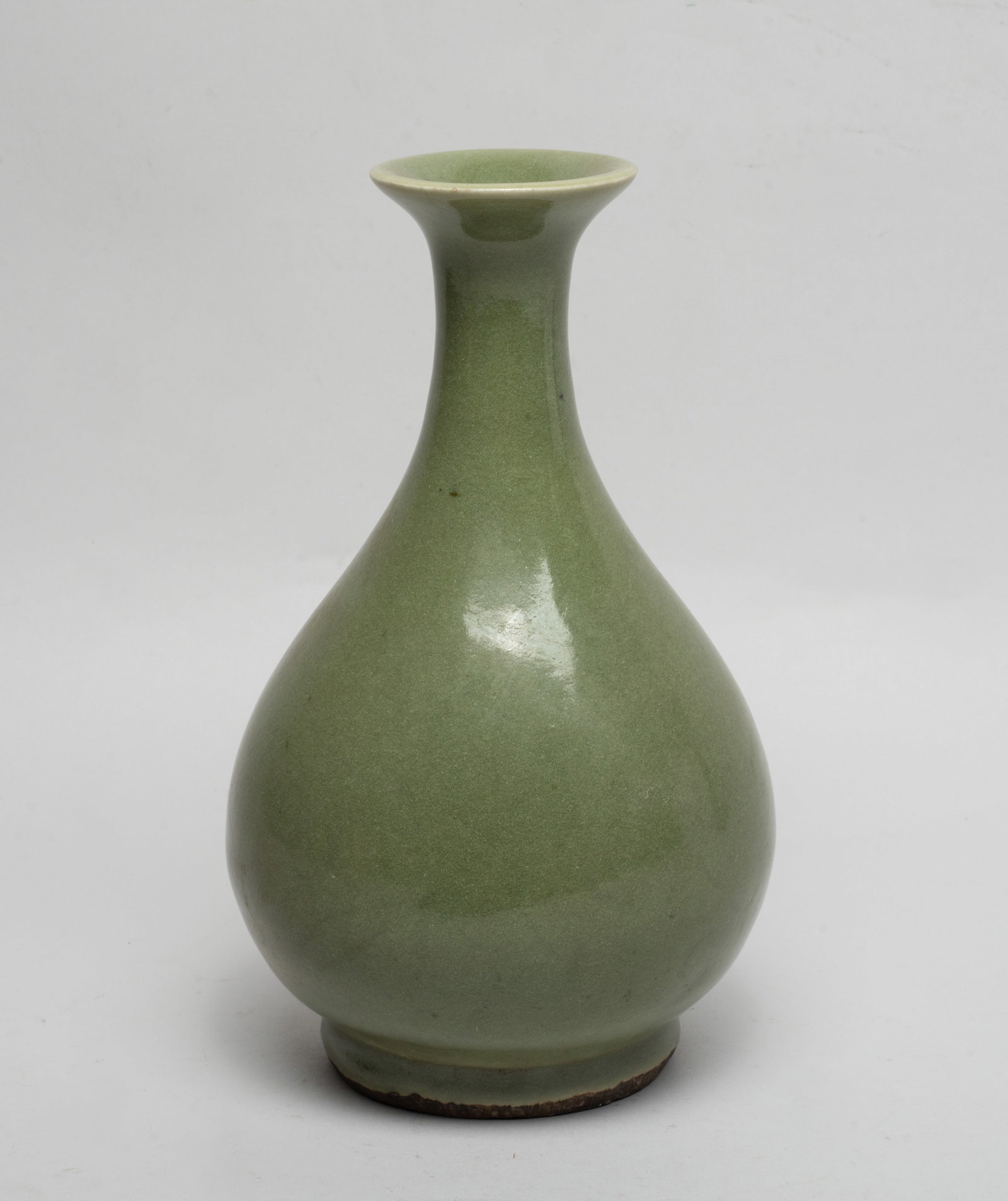 Chinese Longquan Porcelain Vase: The pear-shaped body rising from a short foot to a waisted neck with a flared rim, overall covered in celadon glaze glaze save for the unglazed foot revealing the dark porcelain body. Approx. 8.8*5.2