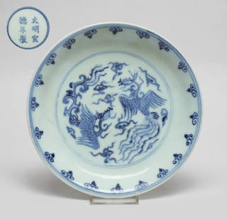 Chinese Export Blue & White Porcelain Plate: The interior painted with a pair of phoenixes amidst clouds, the exterior carved in low relief with a dragon and a phoenix chasing a flaming pearl, the bottom marked with six characters enclosed in do