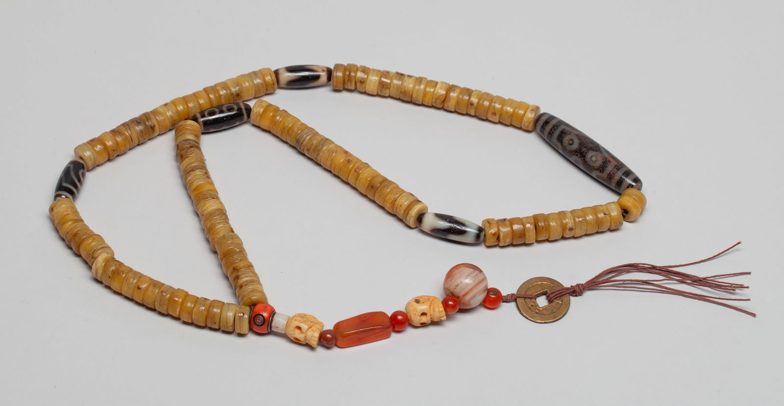 Tibetan/ Chinese Dzi Beads, Mixed Necklace: Long Chinese / Tibetan bead necklace comprised of bone, agate and dzi beads, and a Fengshui coin. Approx. 28 inch L. The Estate of the Store Closed Sale in Little Tokyo, Los Angeles.