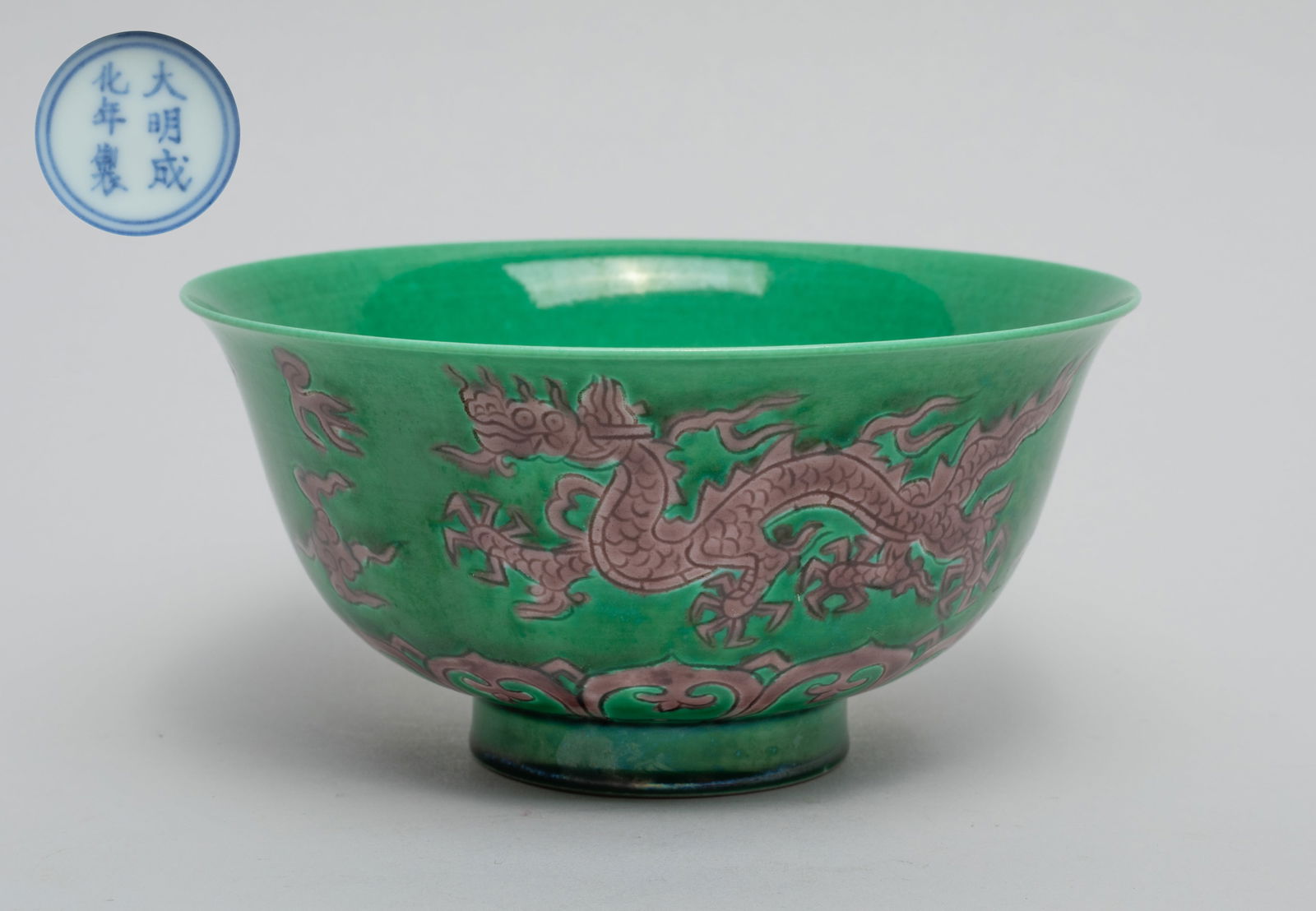 Chinese Export Porcelain Tea Bowl: The tea cup exterior carved in low relief with two dragons pursuing flaming pearls amidst clouds above overlapping lotus petals, glazed in brown color on green glazed ground, the bottom marked with si