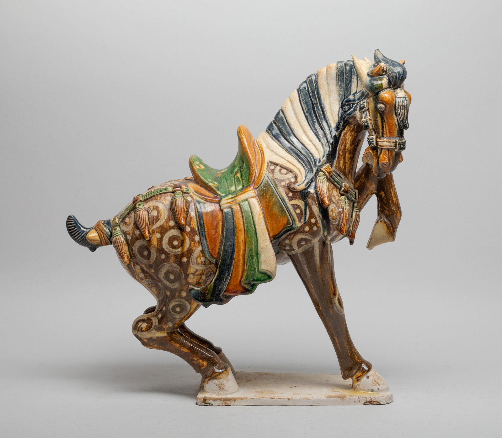 Chinese Sanchai Porcelain Sculpture: Well-modeled, standing on a flat base with left front leg lifting up, the head slightly lowered and turned rightward, with crisply modeled features including large round eyes, open mouth and flared no