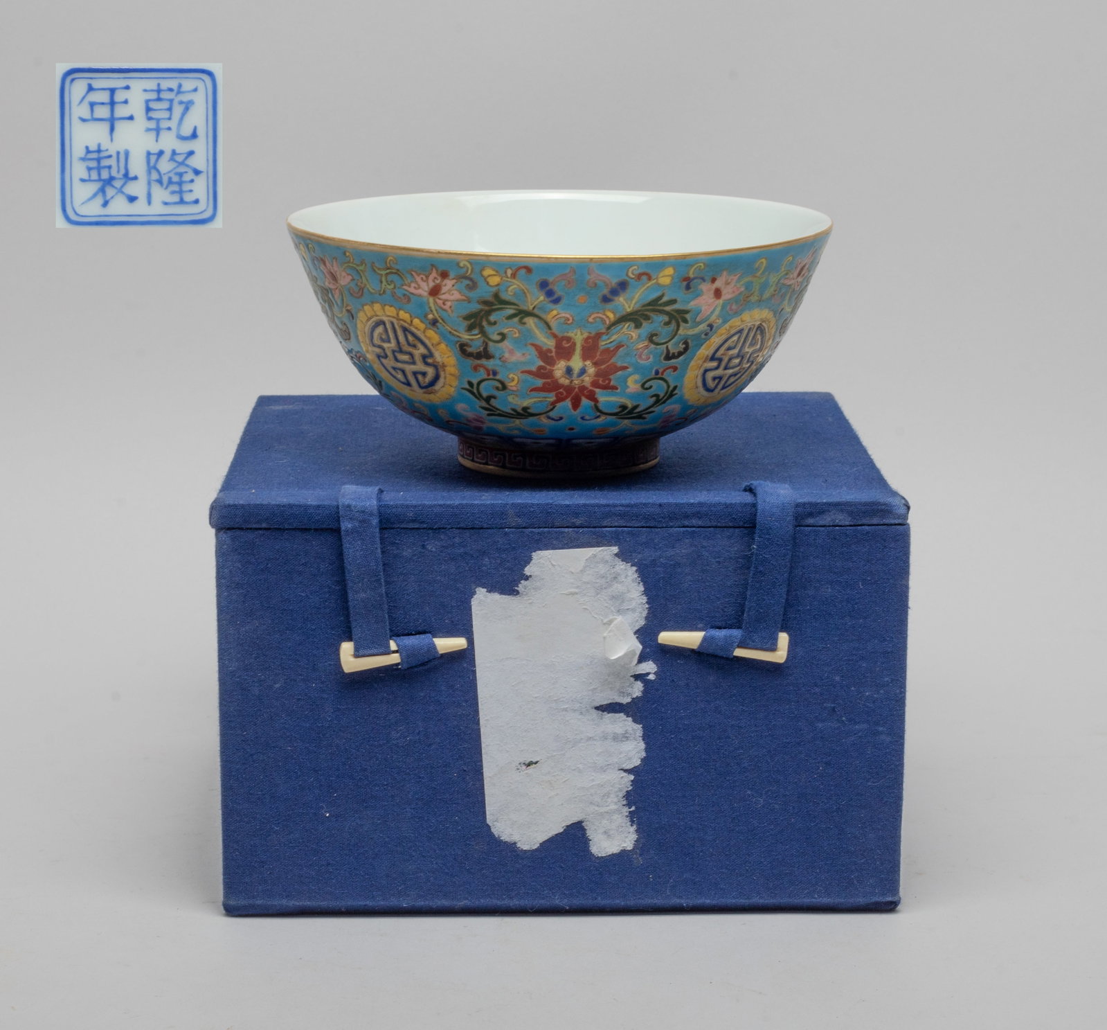 Chinese Export Enameled Porcelain Bowl: The bowl exterior enameled with interlocking lotus scrolls and stylized shou characters above a band of lappets on blue glazed background, the bottom with a seal mark, with box. Approx. 5.8*2.6 inch (
