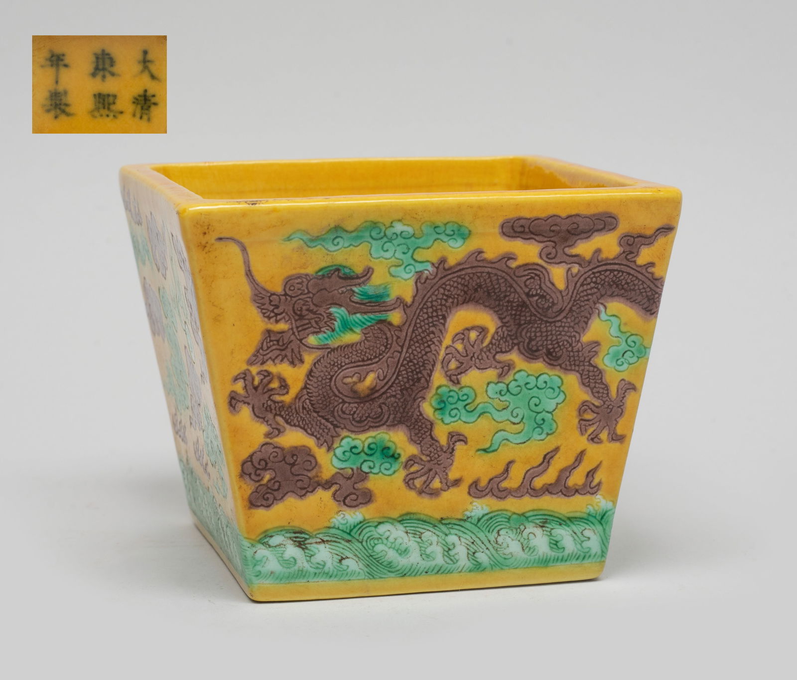 Estate Chinese Sanchai Porcelain Bowl: Of square section, the exterior sides carved in low relief with two dragons pursuing flaming pearls amidst flames and clouds above waves, painted in green and brown colors on yellow glazed background,