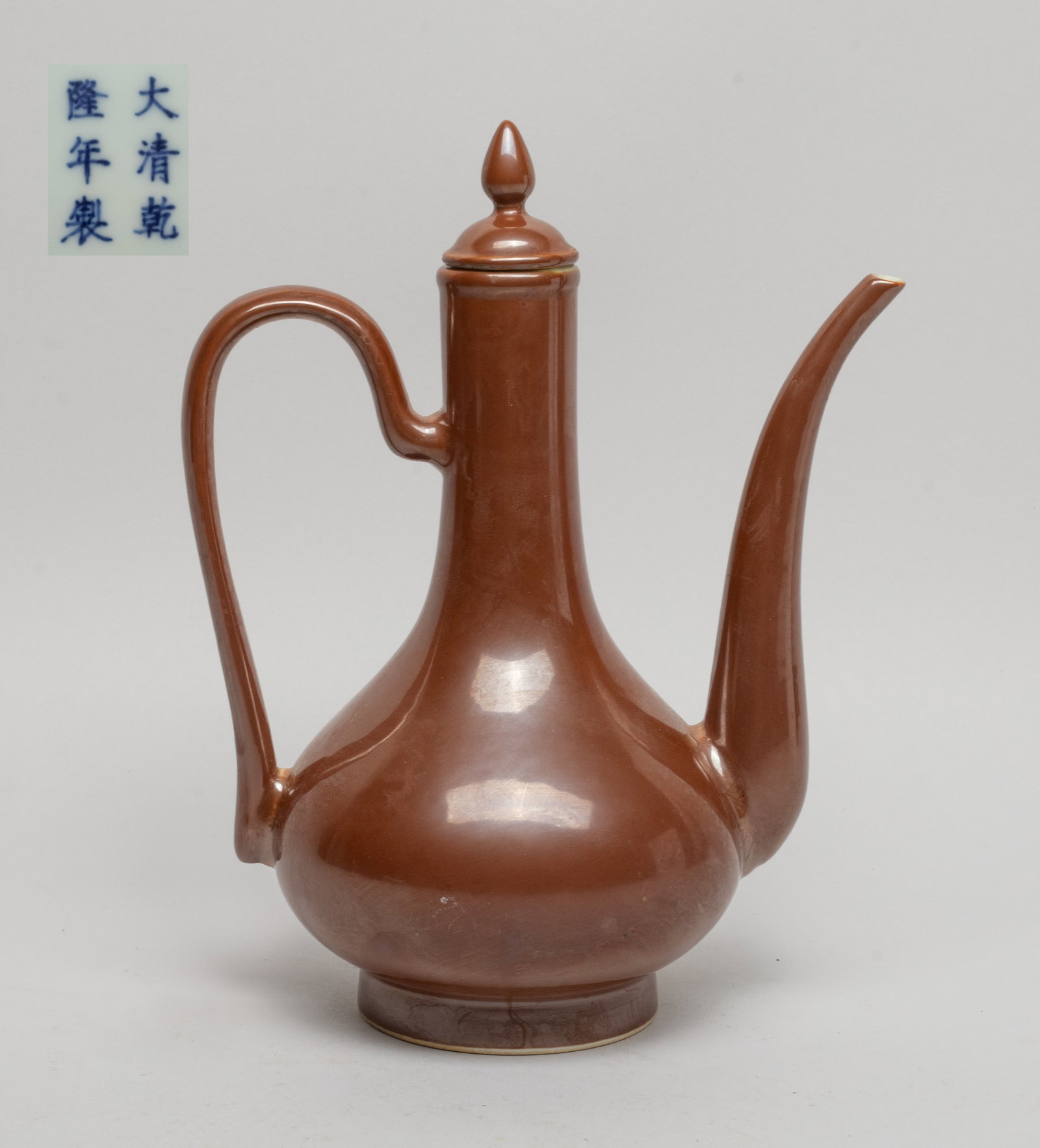 Chinese Brown Glazed Porcelain Wine Pot: The compressed pear-shaped body rising from a short foot to a tall slender neck, the pot and lid exterior applied with even brown glaze, the bottom marked with six characters in underblue glaze. Appro