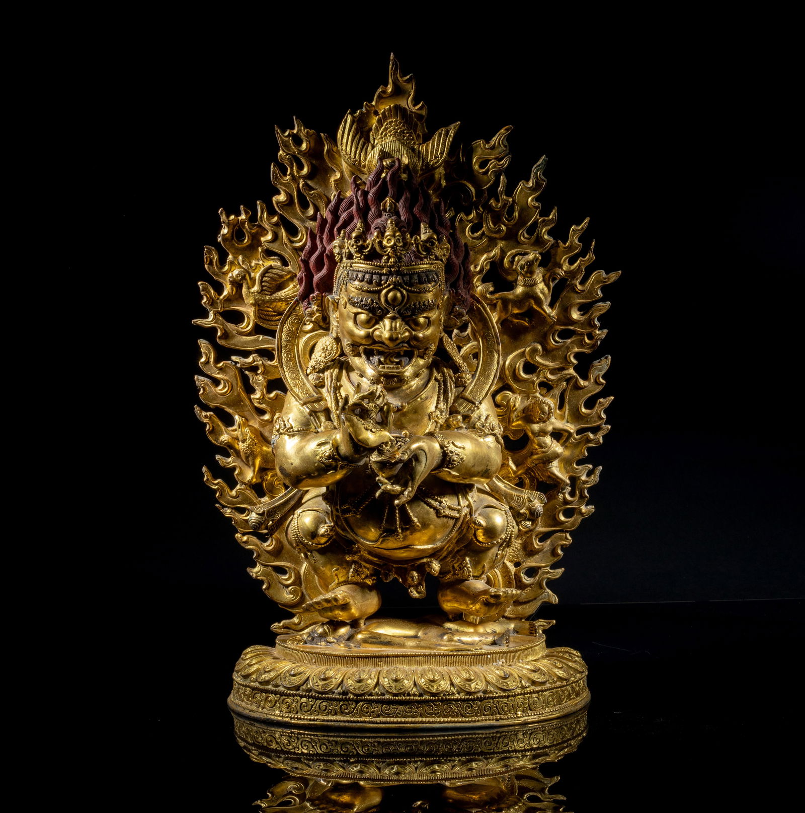 Large Chinese Sino-Tibetan Gilt Bronze Buddha: The Buddha cast in dynamic posture, standing on a lotus pedestal and stepping on a subdued figure beneath, with fierce expression, bulging eyes and flaming hair, the hands holding Buddhist implements,