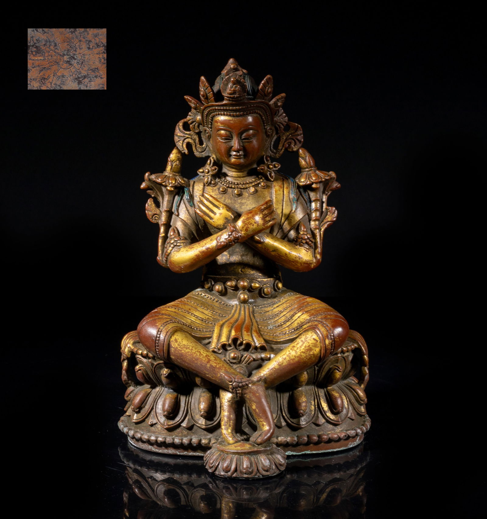 Chinese Gilt Bronze Sculpture of Buddha: The Buddha cast seated on a double-layered lotus base with legs crossed, the arms crossed with hands resting on chest, flanked by stylized lotus around the shoulders, the serene face surmounted with a
