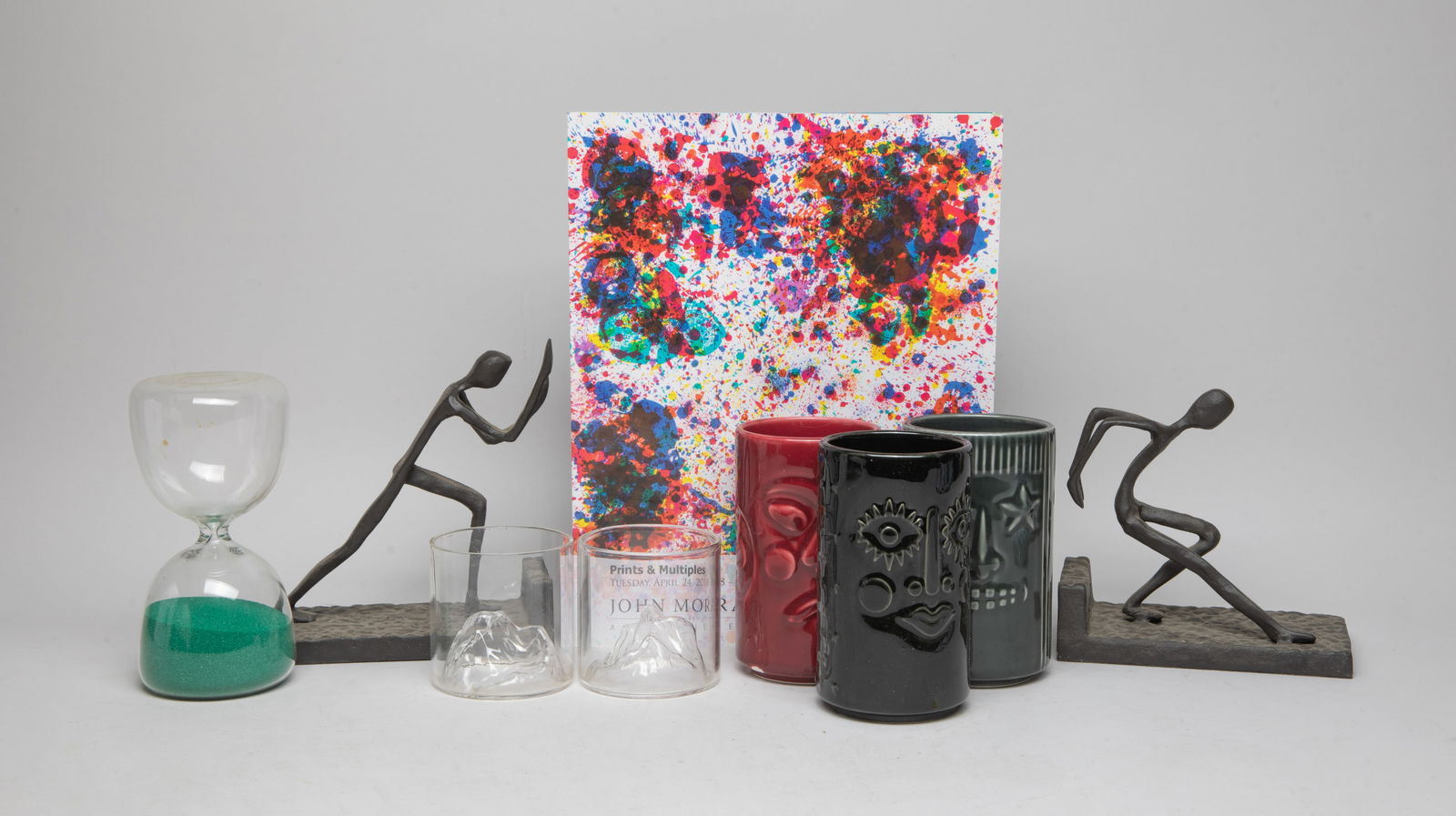 Vintage Art Book, Sculptures & Cups: Including an art auction catalog, two metal sculptures, three tall porcelain cups, two glass cups and a glass hourglass. Size varies.