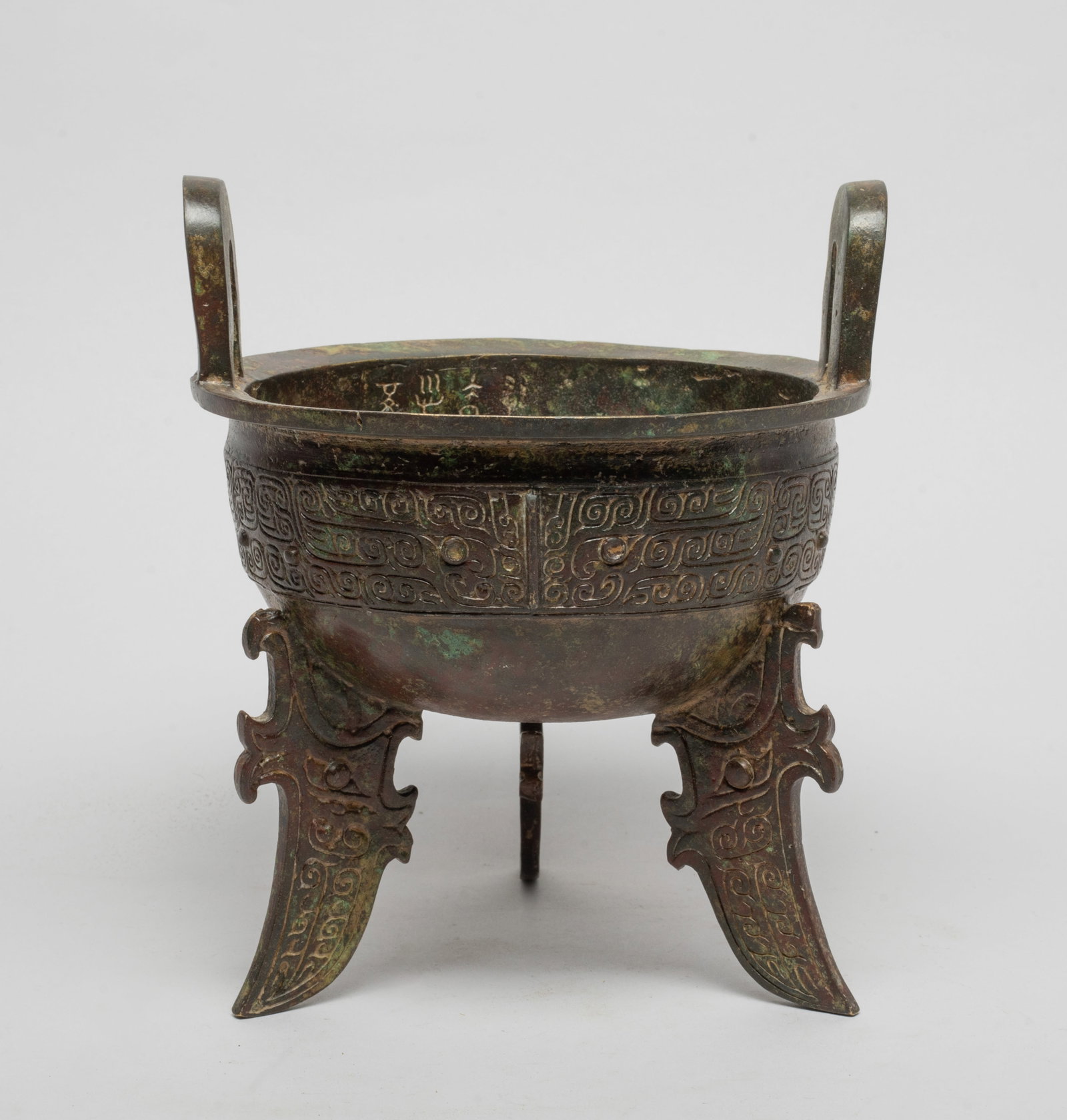 Estate Chinese Bronze Censer: The hemispherical body cast with a band of taotie masks on scrolls ground, supported on three blade legs carved with archaistic motif, surmounted by two upright handles. Approx. 7.5*6.2 inch.