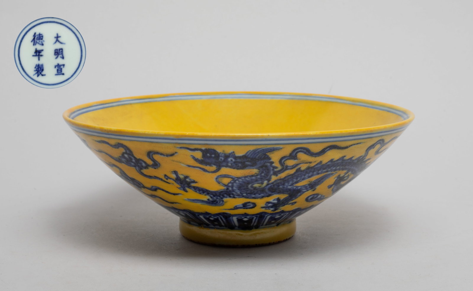 Estate Chinese Export Porcelain Bowl: The exterior painted with dragons sinuous amidst scrolling clouds above a band of lotus petals, the interior centre with scrolling clouds, all against yellow glazed background, the bottom marked with 