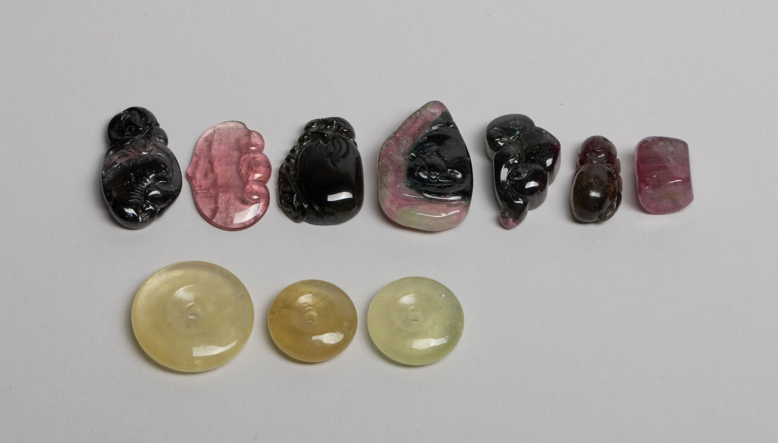Set Chinese Carved Tourmaline Pendants: Set of ten Chinese tourmaline pendants, wherein two carved with lingzhi and bat, two carved with bat and fruit, and two carved in lingzhi form. Approx. 0.88 inch W (largest), 38 gram (total weight). T
