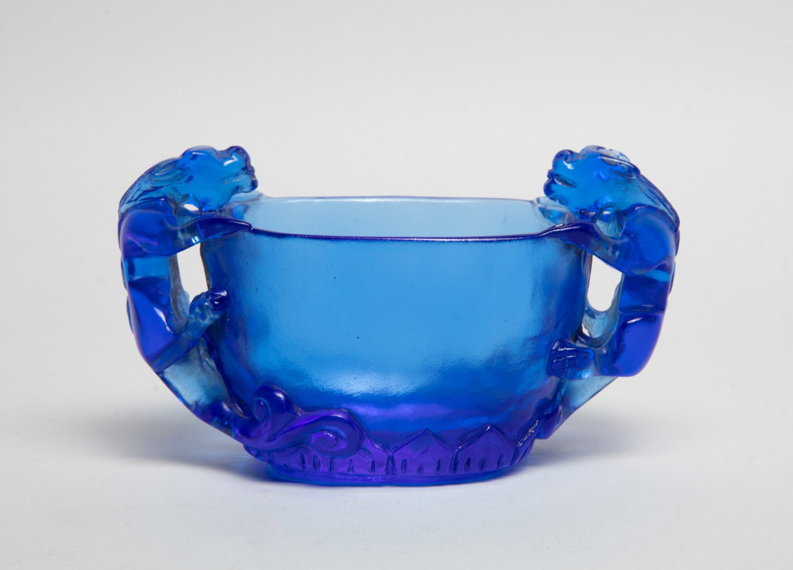 Rare Chinese Peiking Glass Bowl: Chinese blue Peiking glass bowl, with a pair of beasts clambering along the body forming as handles, carved with a band of lotus petals around the foot. Approx. 4.8*2.8*2.3 inch.