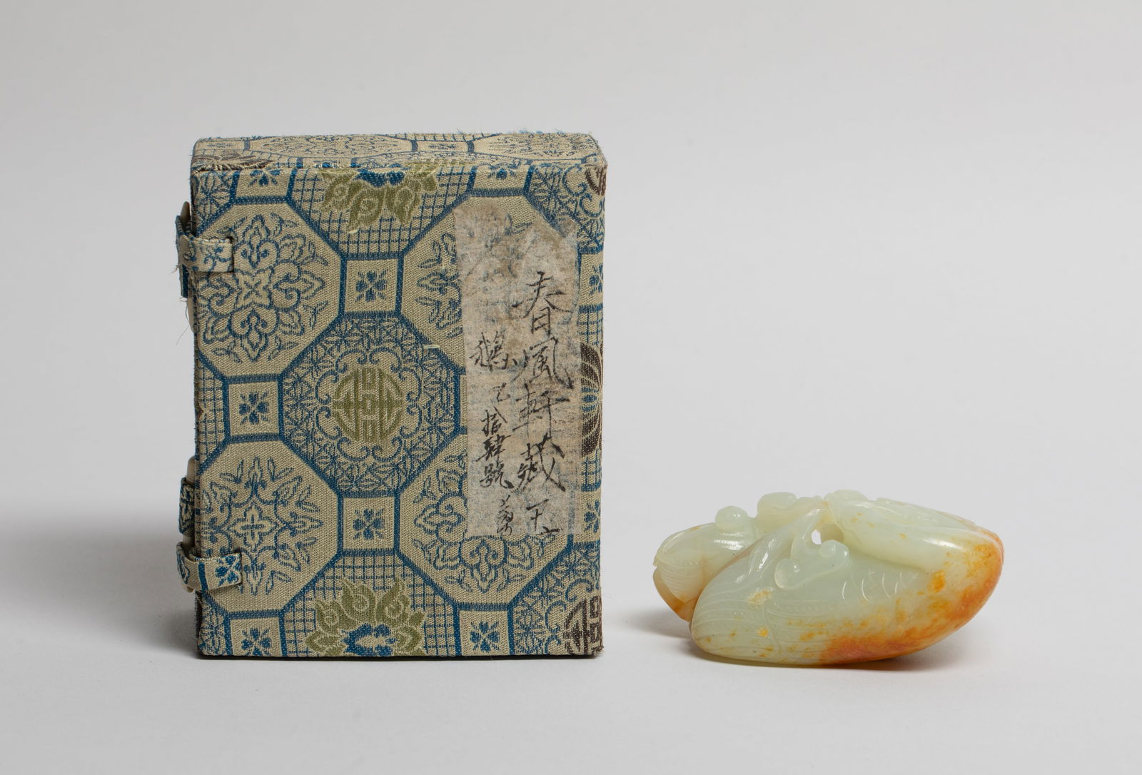 Estate Chinese Russet Jade of Goose: Naturalistically carved as three birds over lotus leaves, grasping lingzhi stems together, with finely incised lines denoting the plumage and feathers, the stone of grey-white tone with russet streaks