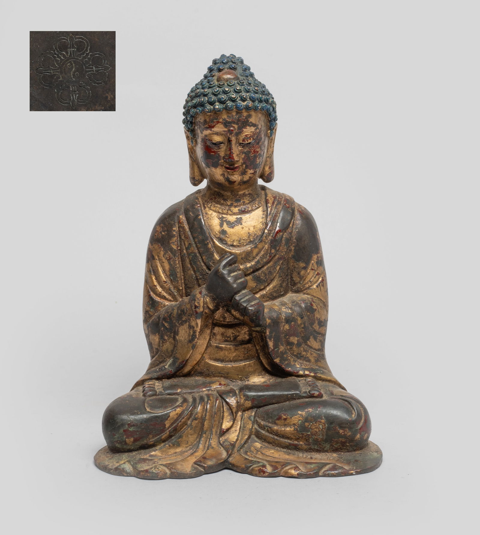 Rare Chinese Painted Bronze Sculpture of Buddha: Chinese painted bronze Buddha, dressed in a loose-fitting robe, the hands in unknown mudra, cast with a serene expression of downcast eyes, iconic pendulous earlobes and tightly rendered hair curls. A