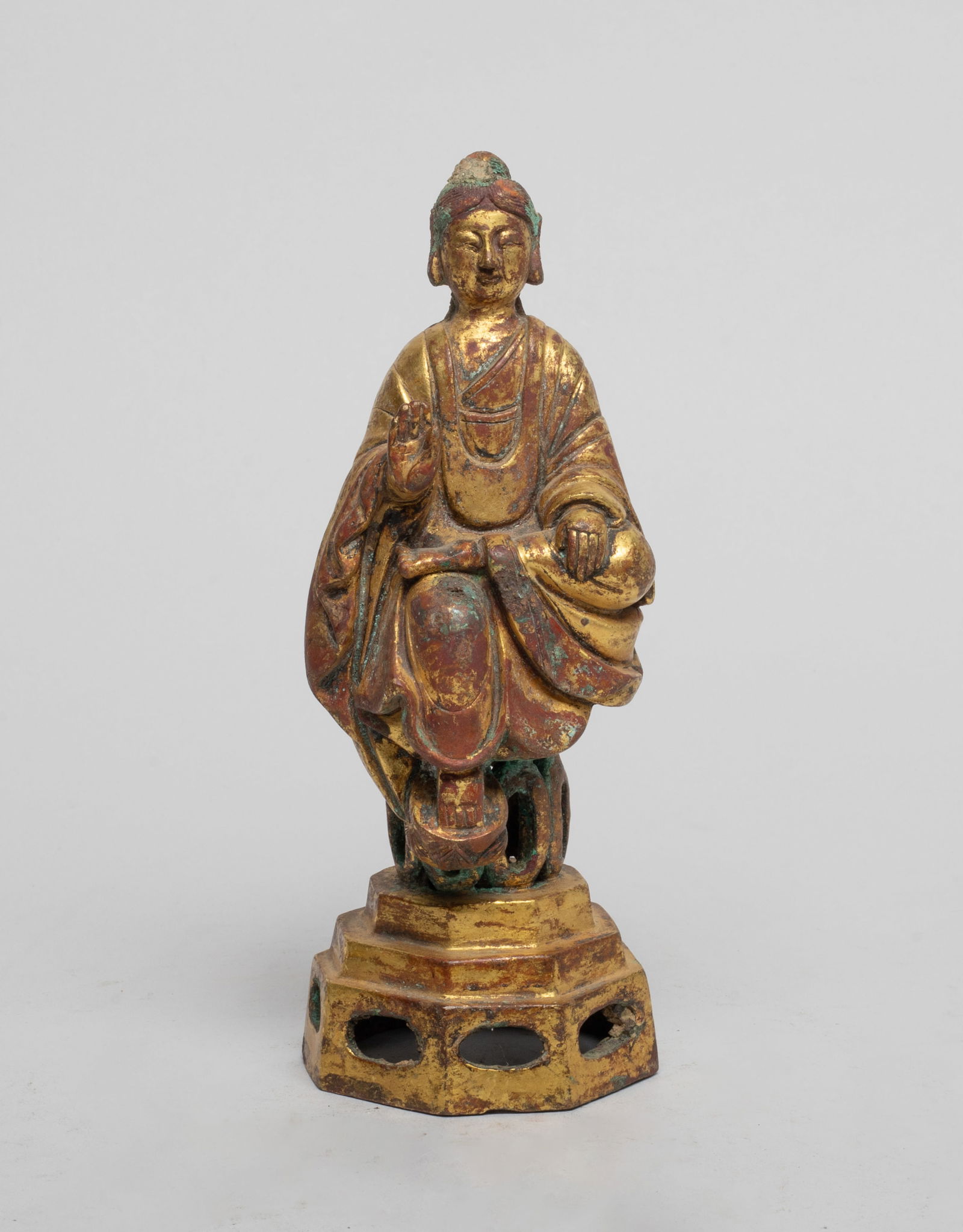 Estate Chinese Gilt Bronze Sculpture of Buddha: The Buddha cast seated on a tall plinth, the left leg bent resting on right knee, wearing a long flowing robe, the left hand placing on leg and right hand in abhaya mudra, the face with serene express