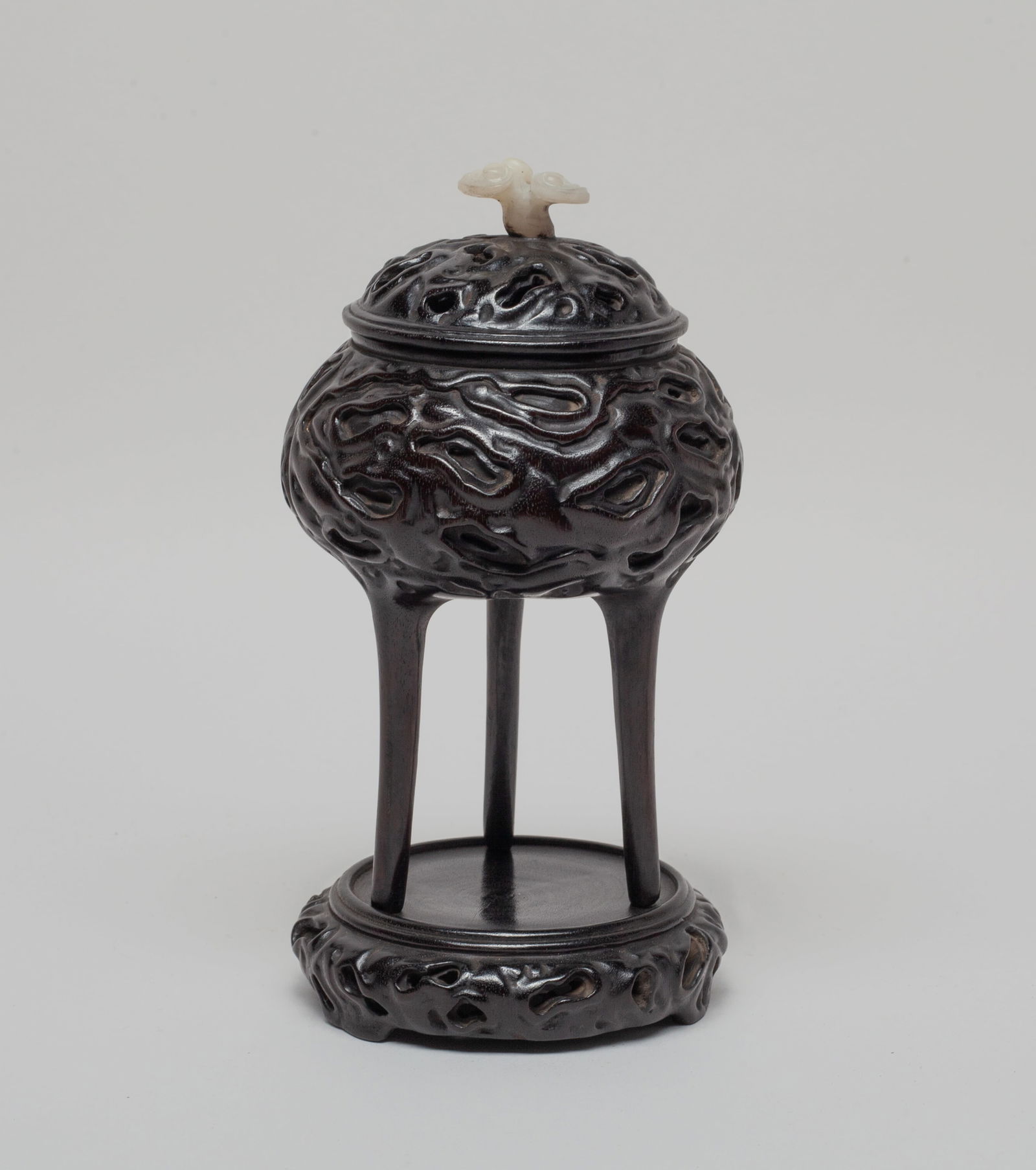 Chinese Zitan Like Wood Carved Censer: Chinese Zitan-like wood censer, of compressed form with three tall cylindrical legs, the exterior carved in form of gnarled wood pattern, the openwork lid surmounted with a white stone carved lingzhi