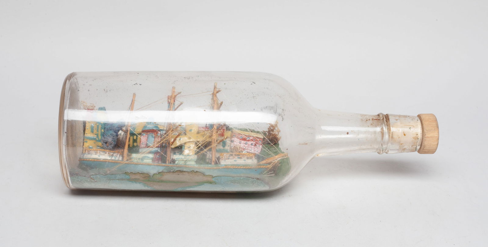 Handmade Whimsical Folk Art Wood in Glass Bottle: Handmade special folk art ship-in-bottle, depicting a ship sailed in front of town. Approx. 11.2*3.6 inch (bottle size).
