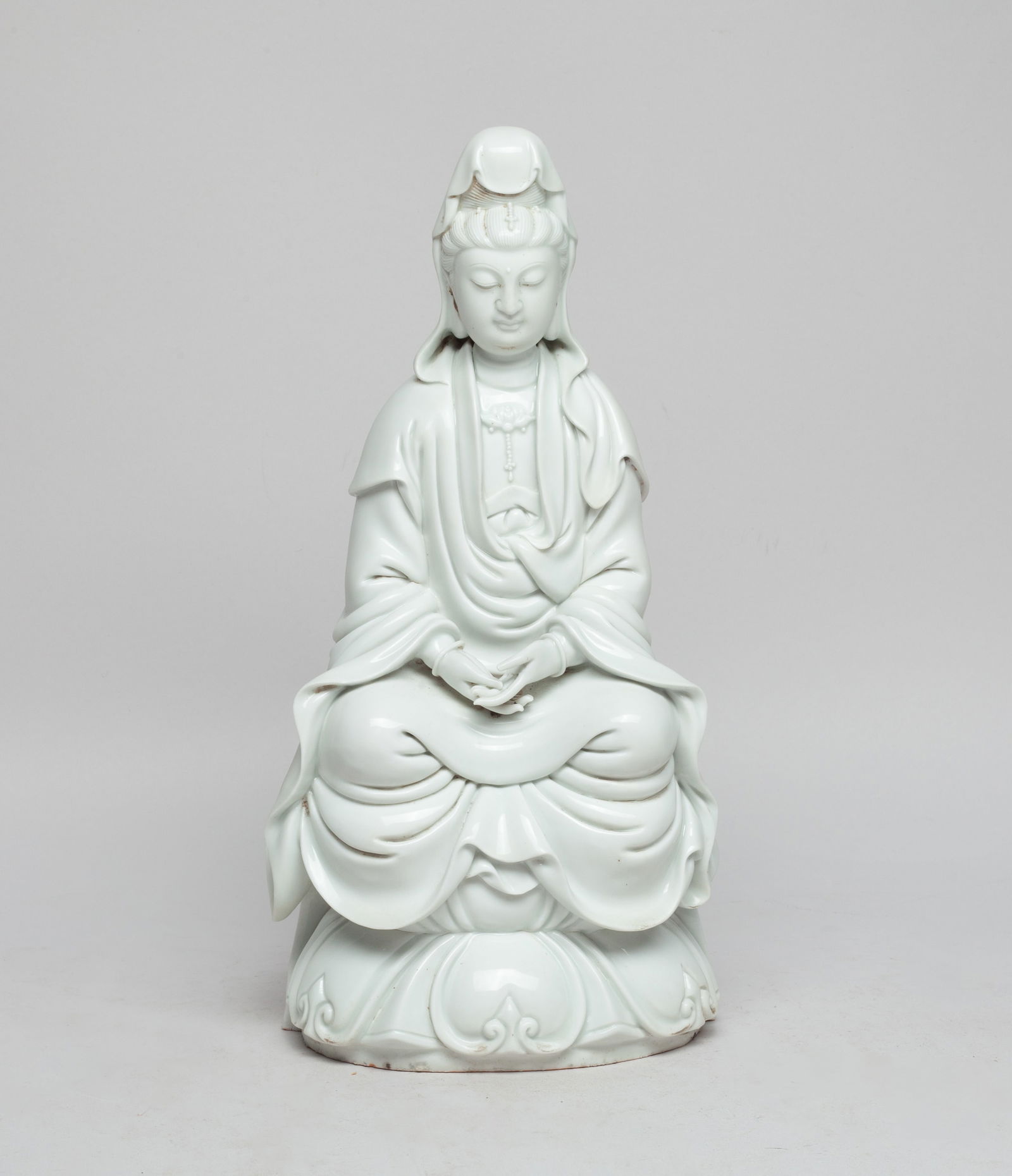 Estate Chinese Blanc De Porcelain Buddha: The Buddha moulded seated on a waisted lotus throne, wearing a long flowing robe open at the chest revealing a lotus necklace and a mantle covering her head and shoulder, the hands in unknown mudra, a