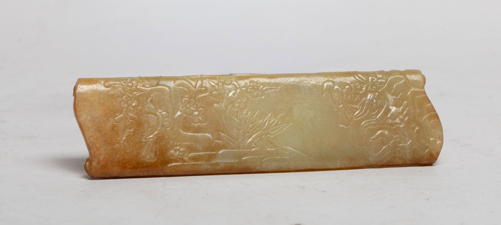 Chinese Russet Jade Long Arm Rest: Carved in on the upper with lingzhi, bamboo and plum blossoms issuing from rockery, a bird on the branch, the lower carved with lingzhi issuing from rockery, a bird on the fungus. Approx. 5.8*1.55 inc