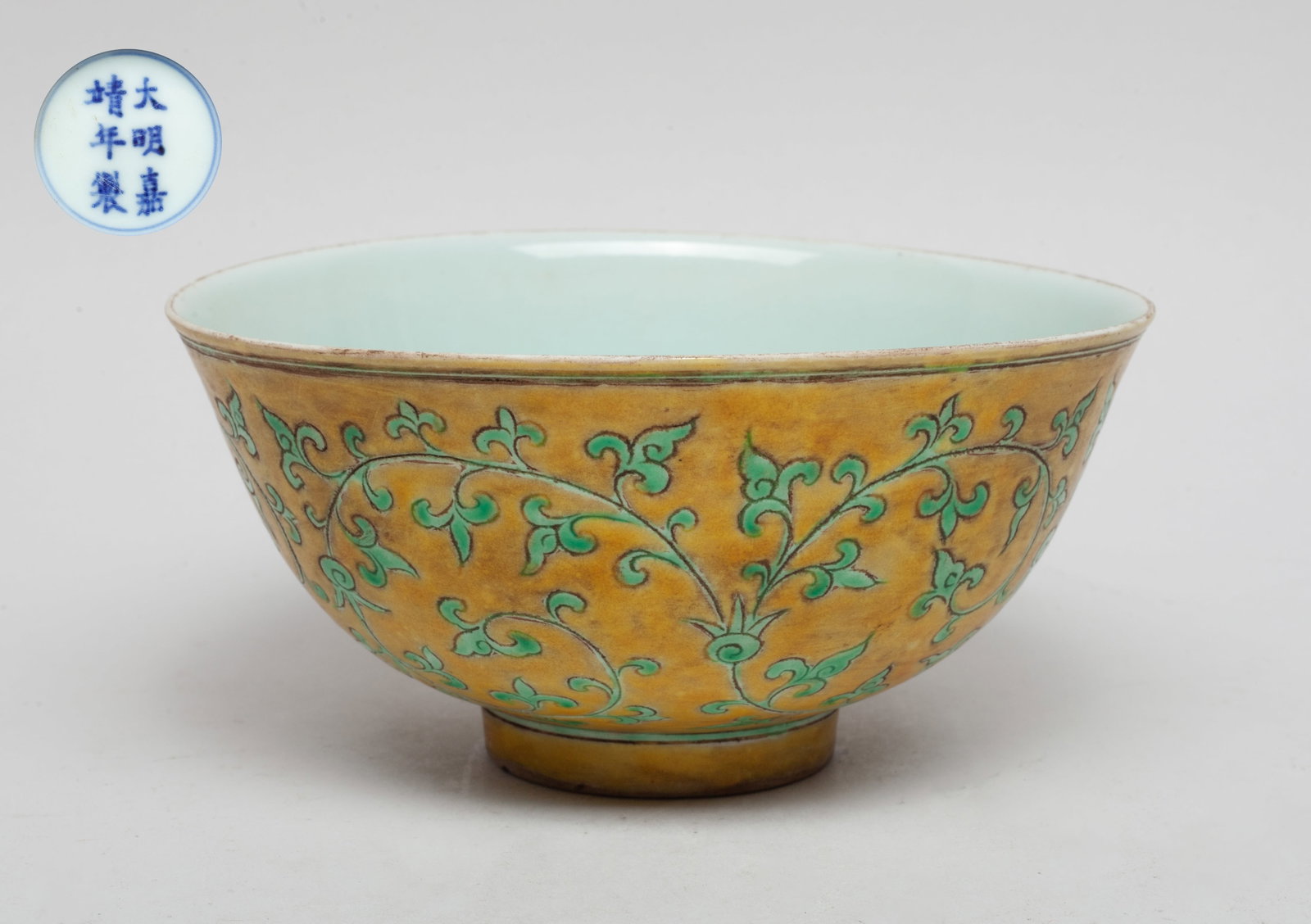 Chinese Export Porcelain Bowl: The bowl exterior incised and painted with undulating leafy sprays on yellow brown background, the interior covered with pale sea-green glaze, the bottom marked with six characters enclosed in double 