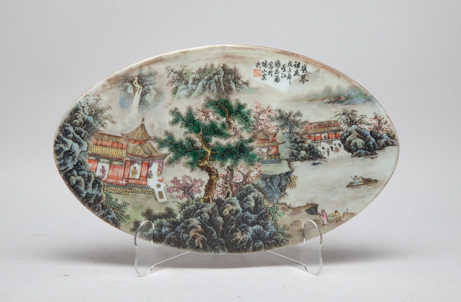 Chinese Famille Rose Porcelain Plate: Of oval shape, enameled and painted with figures standing inside pavilions, among trees and rocks along the riverbank, inscribed with related passages. Approx. 12.7*7.7 inch.