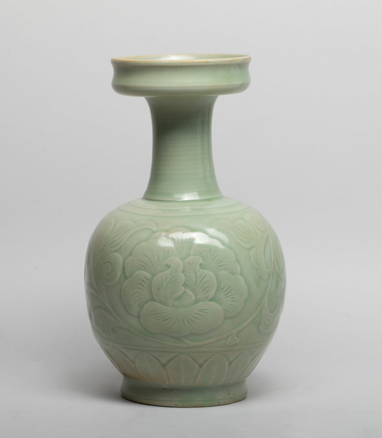Estate Chinese Shipwreck Type Porcelain Vase: The ovoid body rising from a short foot to a gently waisted neck with a dished rim, the body carved in low relief with a long leafy stem issuing a flower bloom, above a band of leaves, overall covered