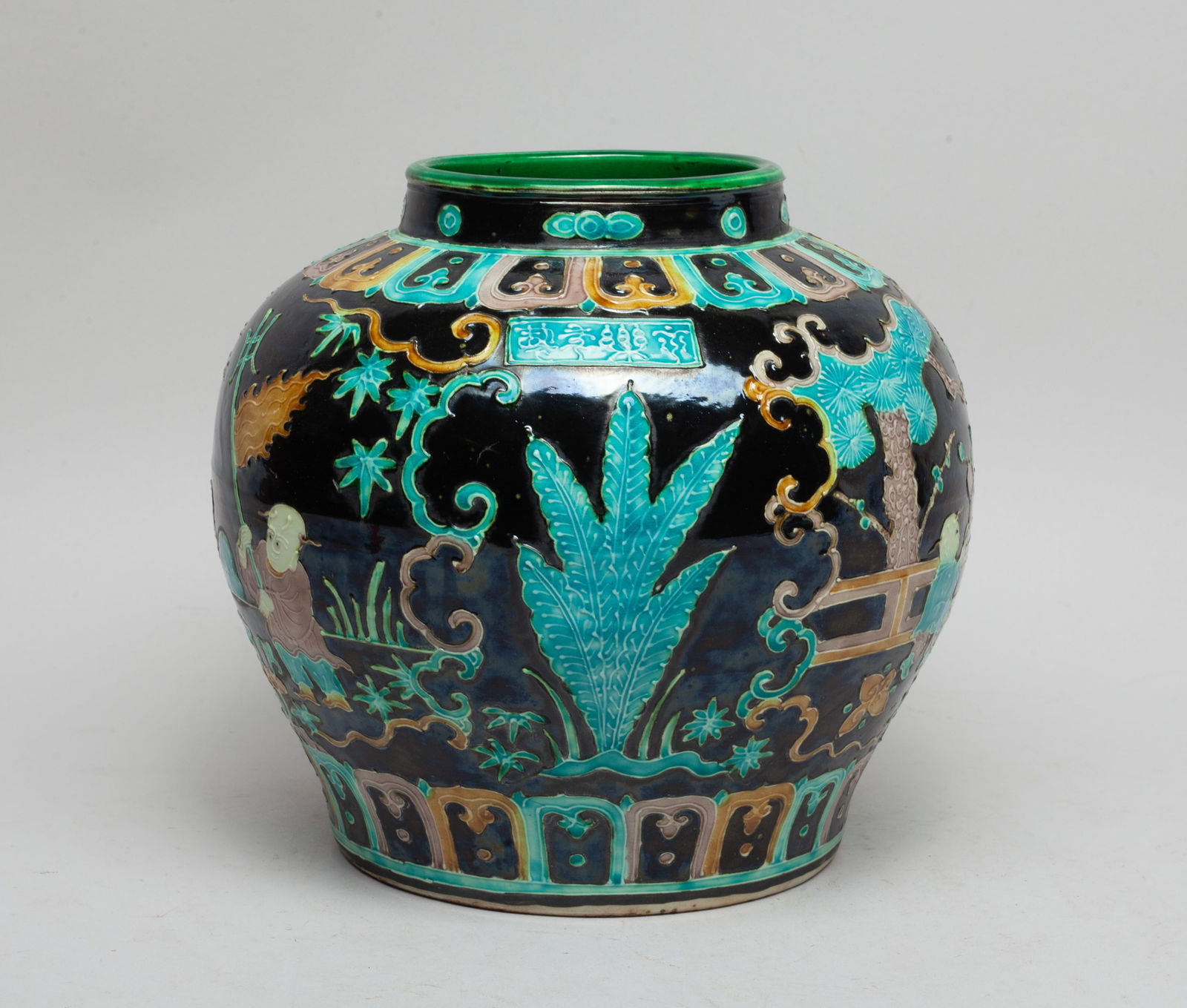 Chinese Fahua Glazed Porcelain Jar: The exterior decorated with boys playing games among trees and lingzhi, between bands of petals, inscribed with a four-character mark, all against black glazed background, the interior green glazed. A