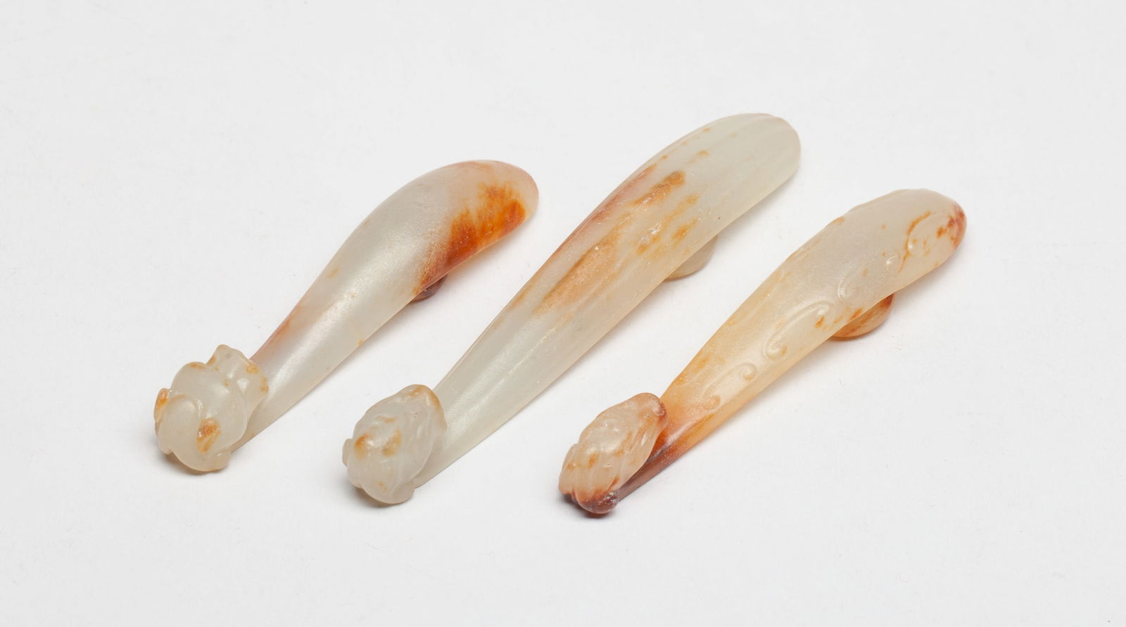 Set Chinese Jade/ Stone Belt Buckles: Set of three Chinese russet jade / stone belt buckles, each carved with a bird head, the underside with a circular knob. Approx. 3.68*0.6 inch (largest).