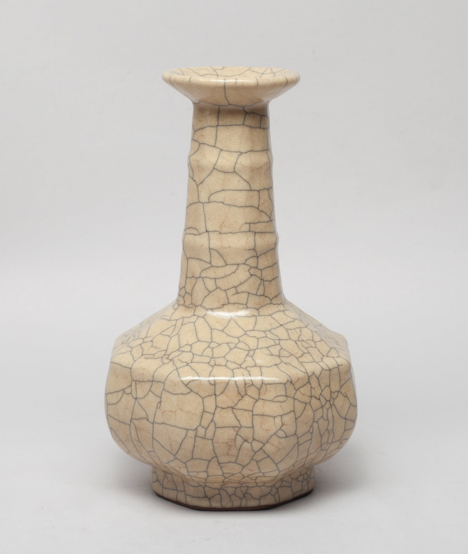 Estate Chinese Ge Ware Porcelain Vase: Of octagonal section, the compressed body rising from a short foot to a tall neck with a flared rim, overall covered in beige glaze suffused with a matrix of black crackles. Approx. 7.8*4.7 inch.