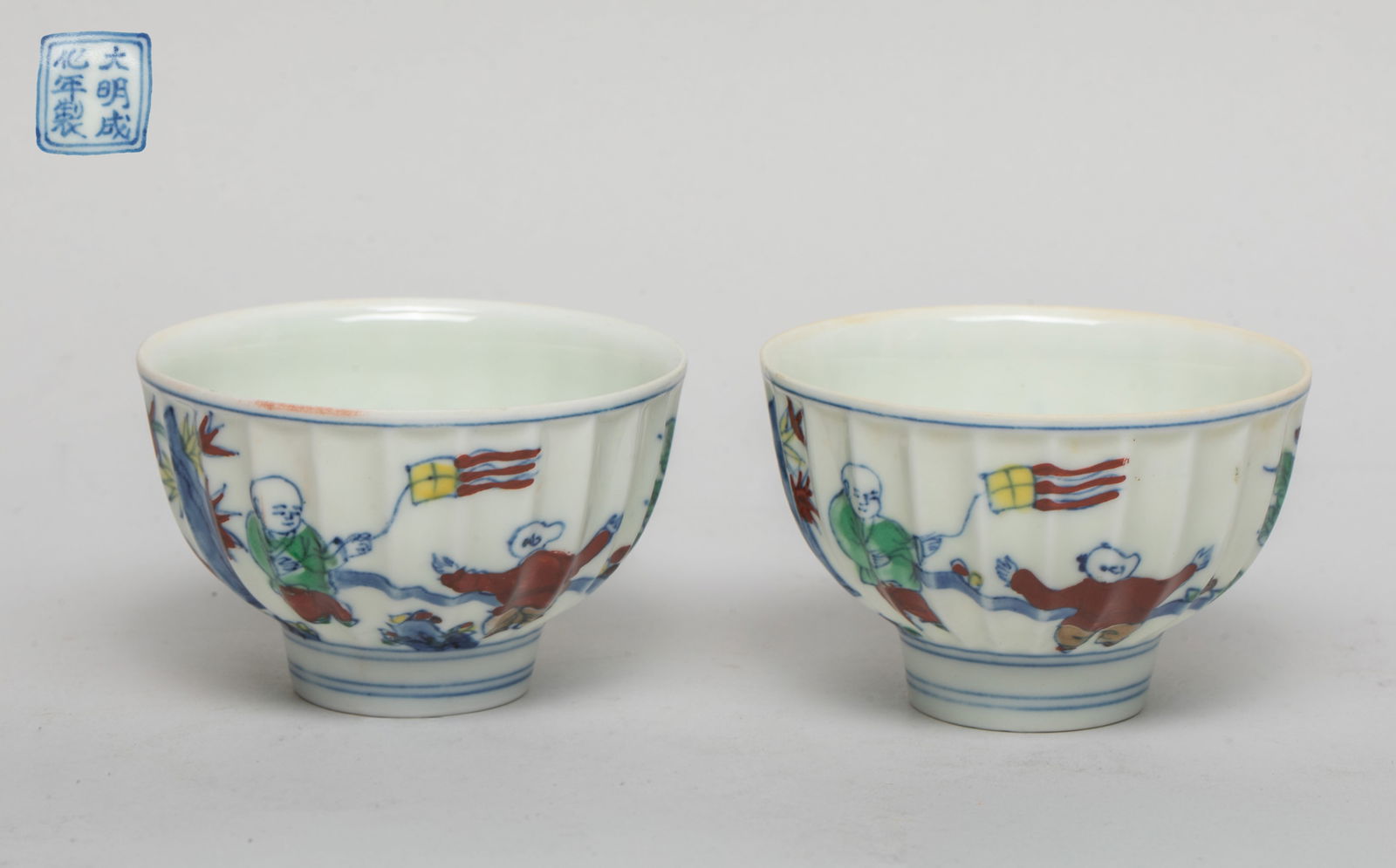 Pair Chinese Export Porcelain Tea Cups: A pair of tea cups of lobed form, the exterior painted with boys playing games, the bottom inscribed with seal marks. Approx. 2.9*1.8 inch (each).