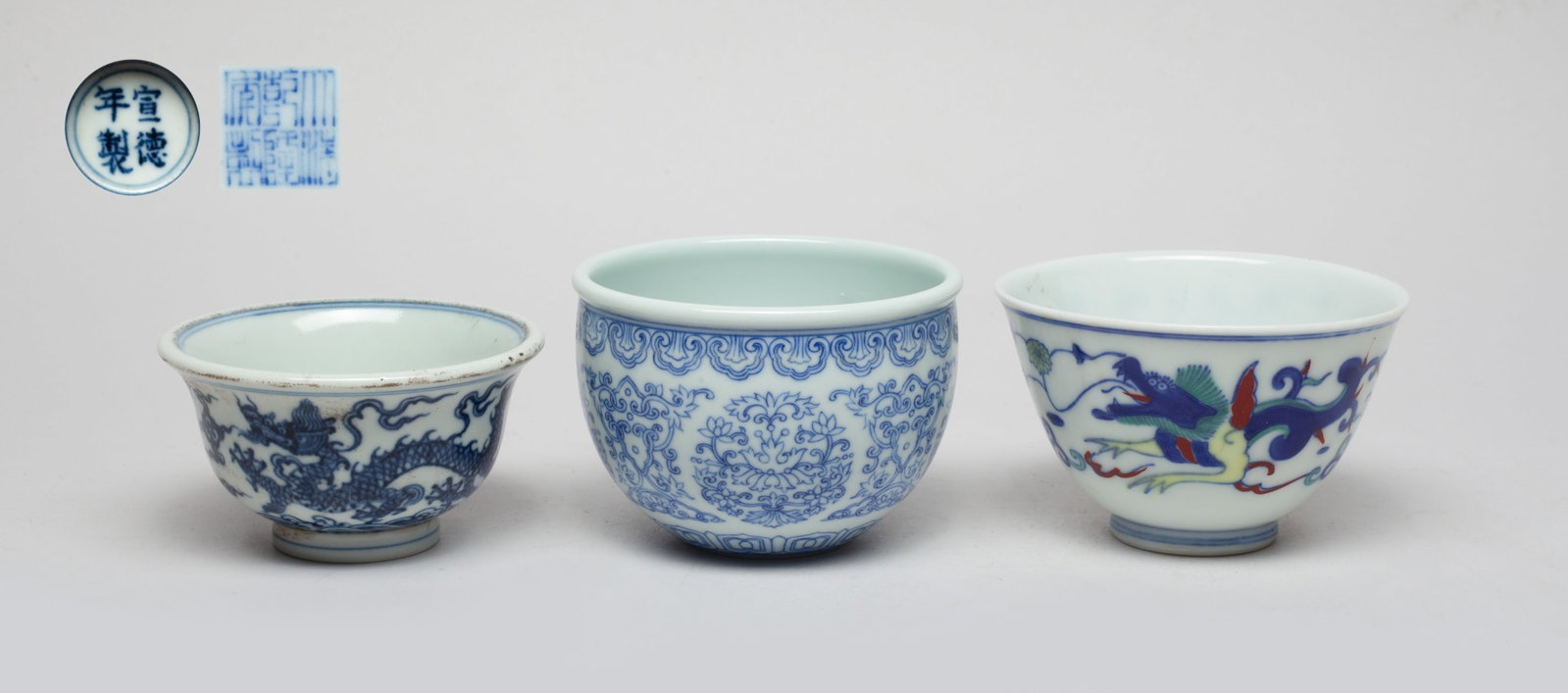 Set Chinese Export Porcelain Cups: Three cups as a set, one cup exterior painted with lotus foliage between bands of ruyi heads and petals, with a six-character mark on the bottom, one cup exterior painted with dragons amidst clouds ab