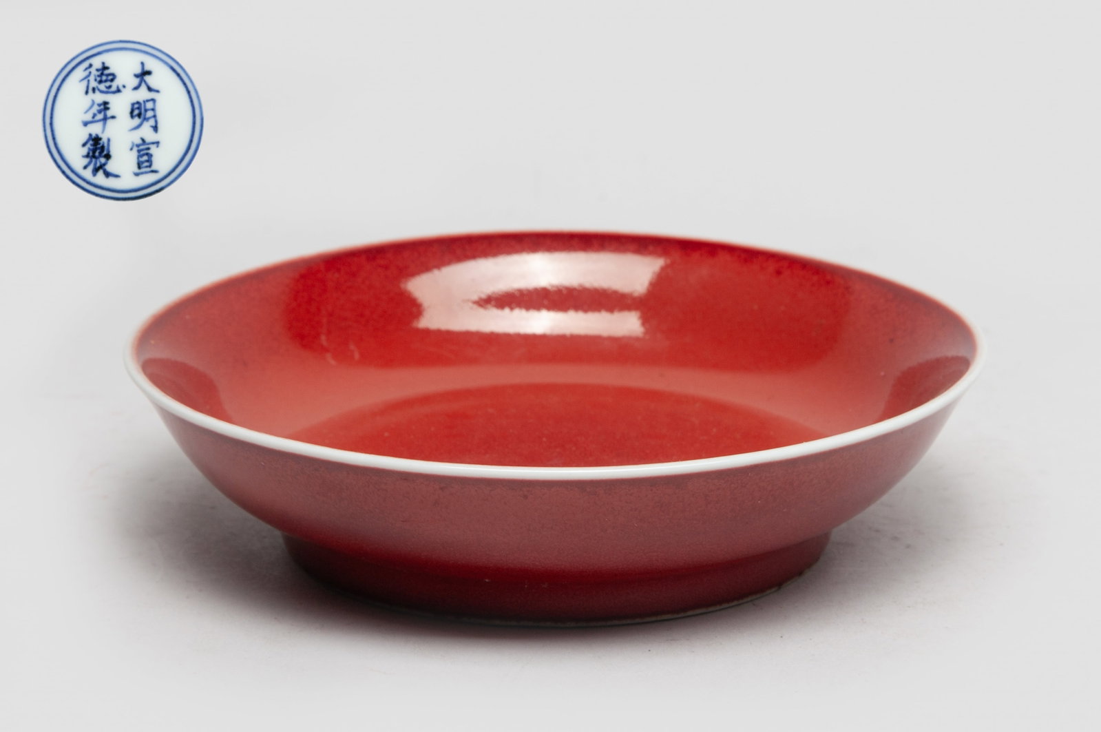 Chinese Red Glazed Porcelain Plate: The plate inside and out applied in mottled red glaze, the bottom marked with six characters enclosed in double circles in underblue glaze on white ground. Approx. 5.9 inch D.