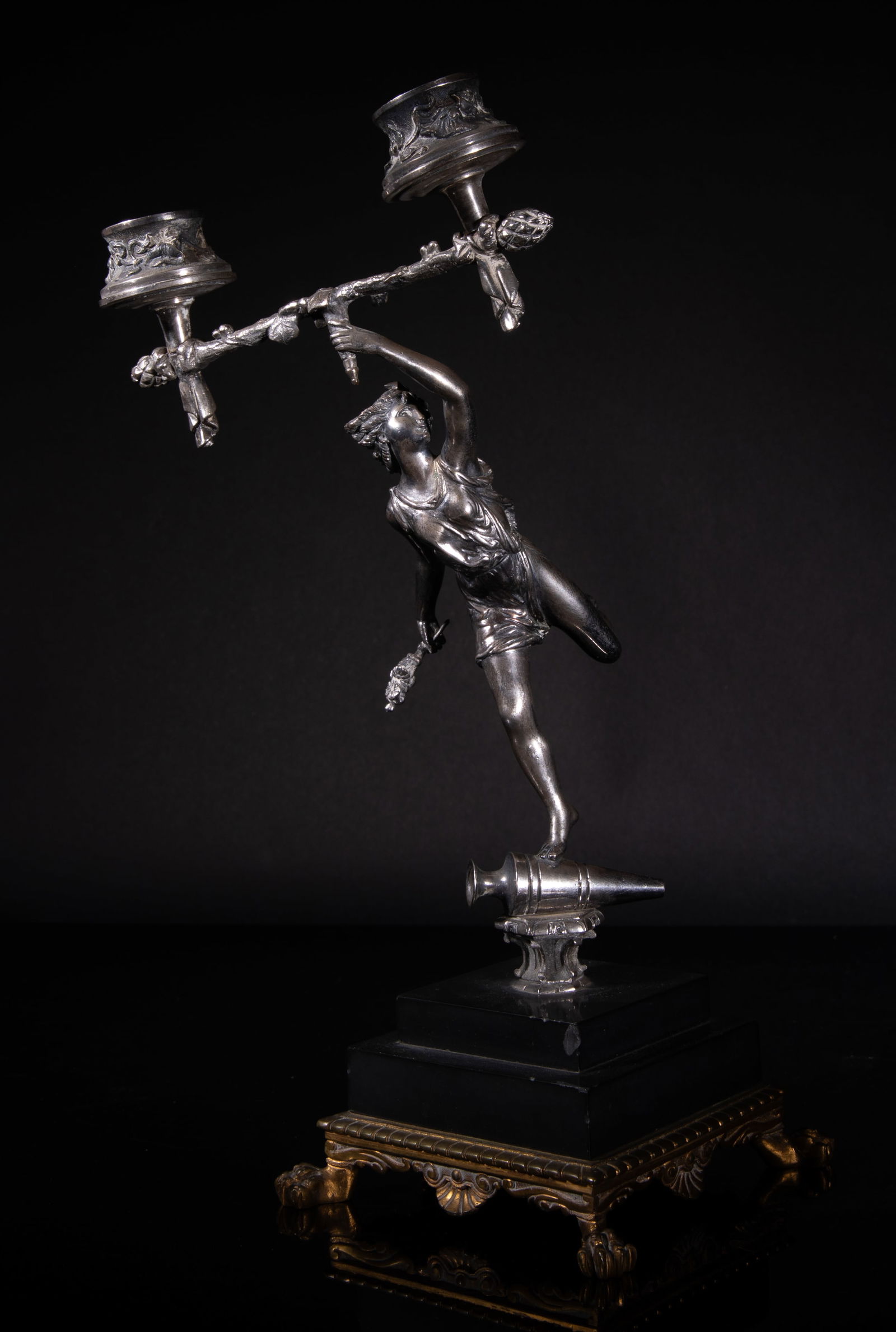 Vintage Sculpture Statue Candelabra Greek Goddess: The Greek goddess statue cast stepping on a vase with right leg, and left leg kicking back, her left hand holding the candlestick holders, and right hand grasping a cluster of flowers, with a square b