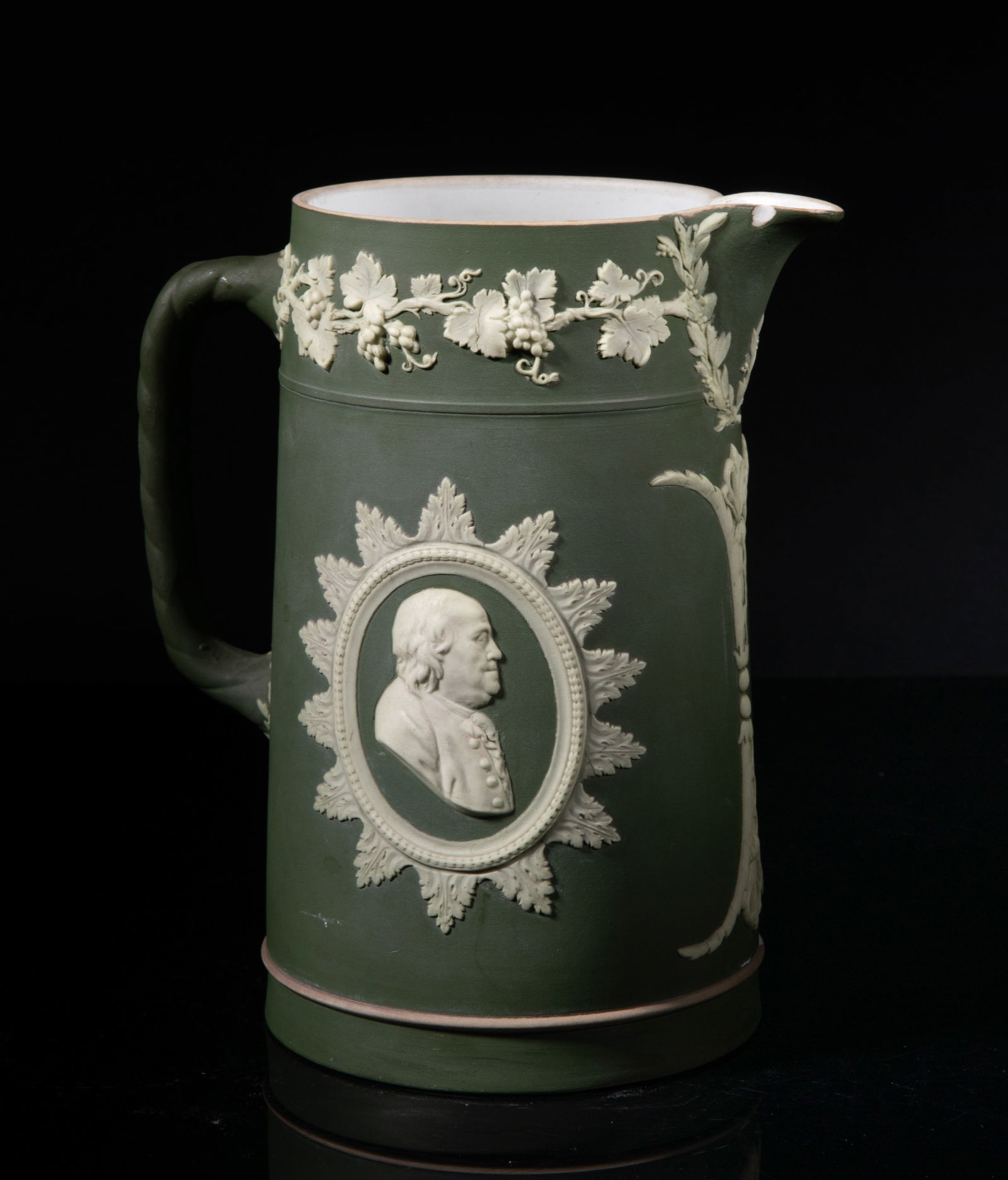 Early 1900s Wedgwood Jasper Ware Pitcher: Vintage jasper ware pitcher, the exterior carved with the figural portraits and grape vines on green background, the bottom marked ENGLAND WEDGWOOD. Approx. 7.5*6.4*4.4 inch. The Estate of the Matte &