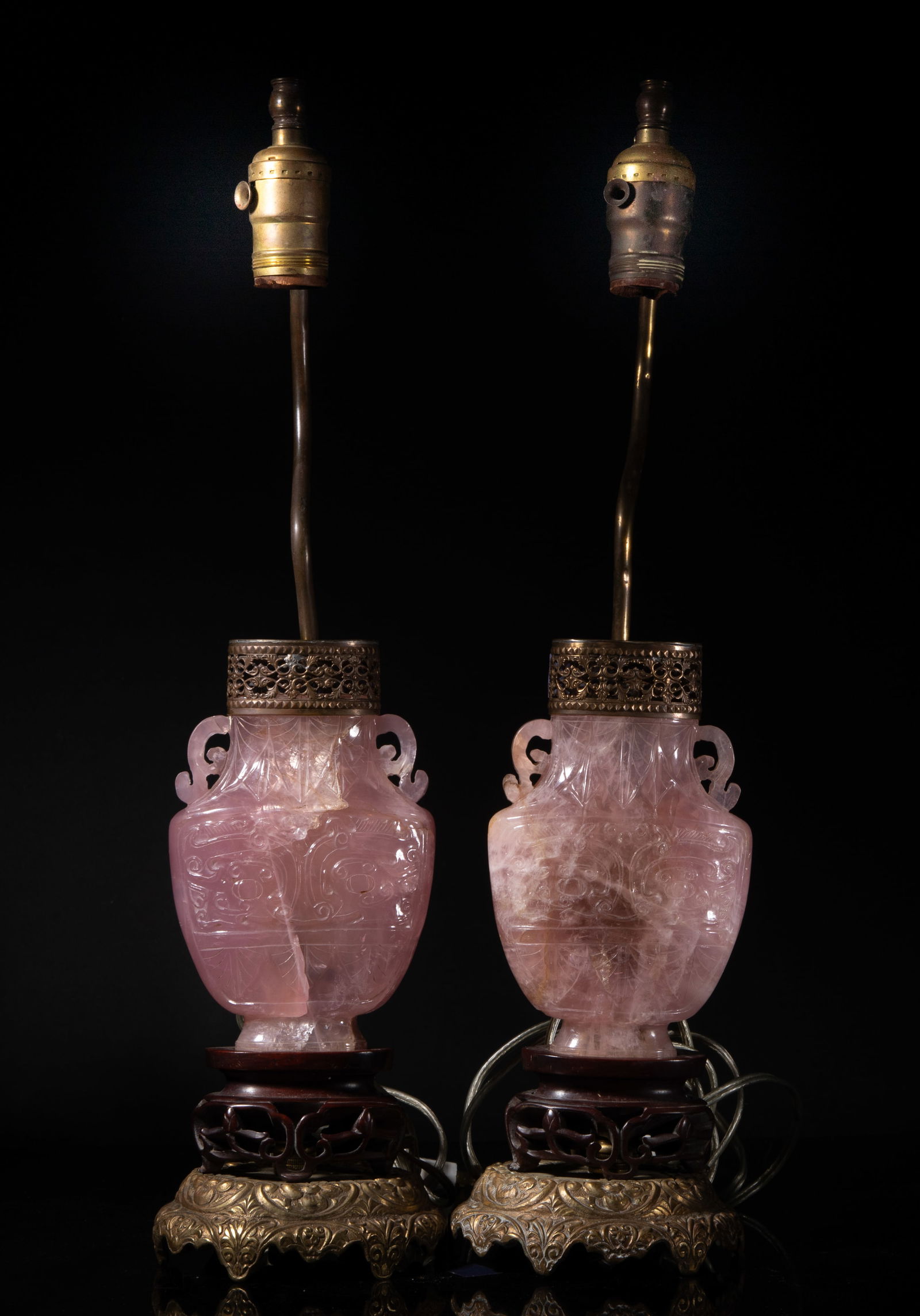 Two Chinese Rose Quartz Vases Lamps: Two rose quartz vase form table lamps, the body of flattened ovoid shape rising from splayed foot to columnar neck with two handles, either side carved with a taotie mask between leaves, the base cast