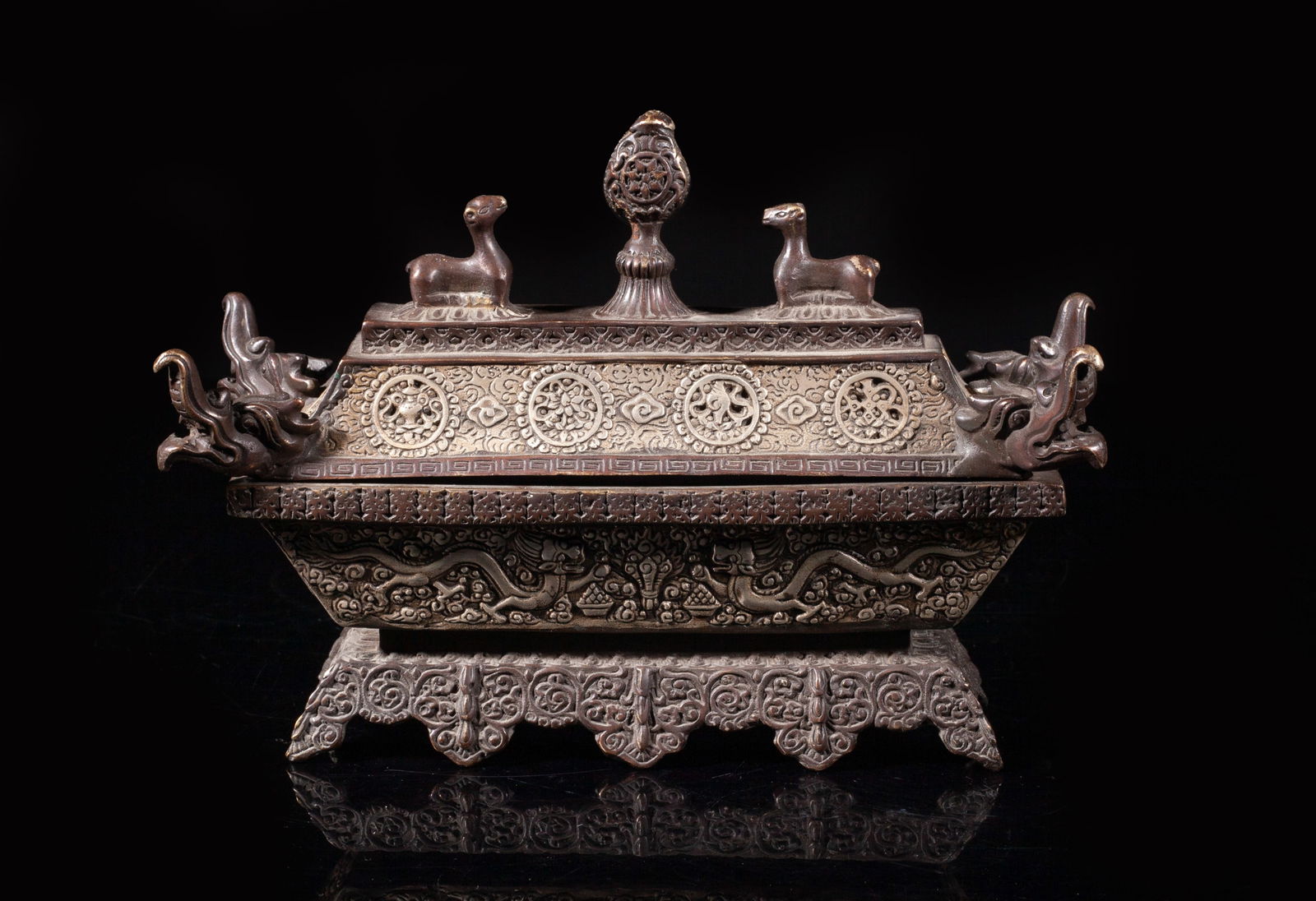 Estate Chinese/ Tibetan Bronze Case: Of tapered rectangular section, the body carved with dragons among scrolls, the foot worked in ruyi head form, the cover carved with Buddhist treasures, cast with a dragon head at each corner, surmoun