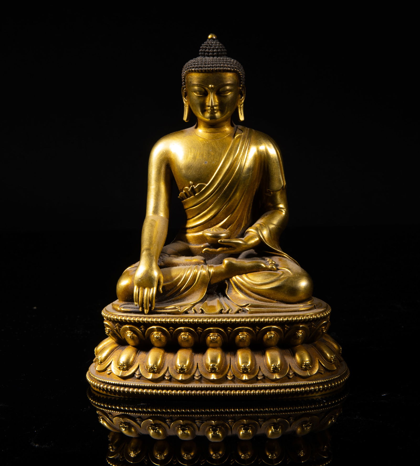 Estate Chinese Gilt Bronze Sculpture of Buddha: Cast seated in meditation on a waisted lotus throne, his left hand holding an elm bowl and right hand in bhumisparsa mudra, wearing a loose-fitting robe open at the right arm, the base with a Buddhist