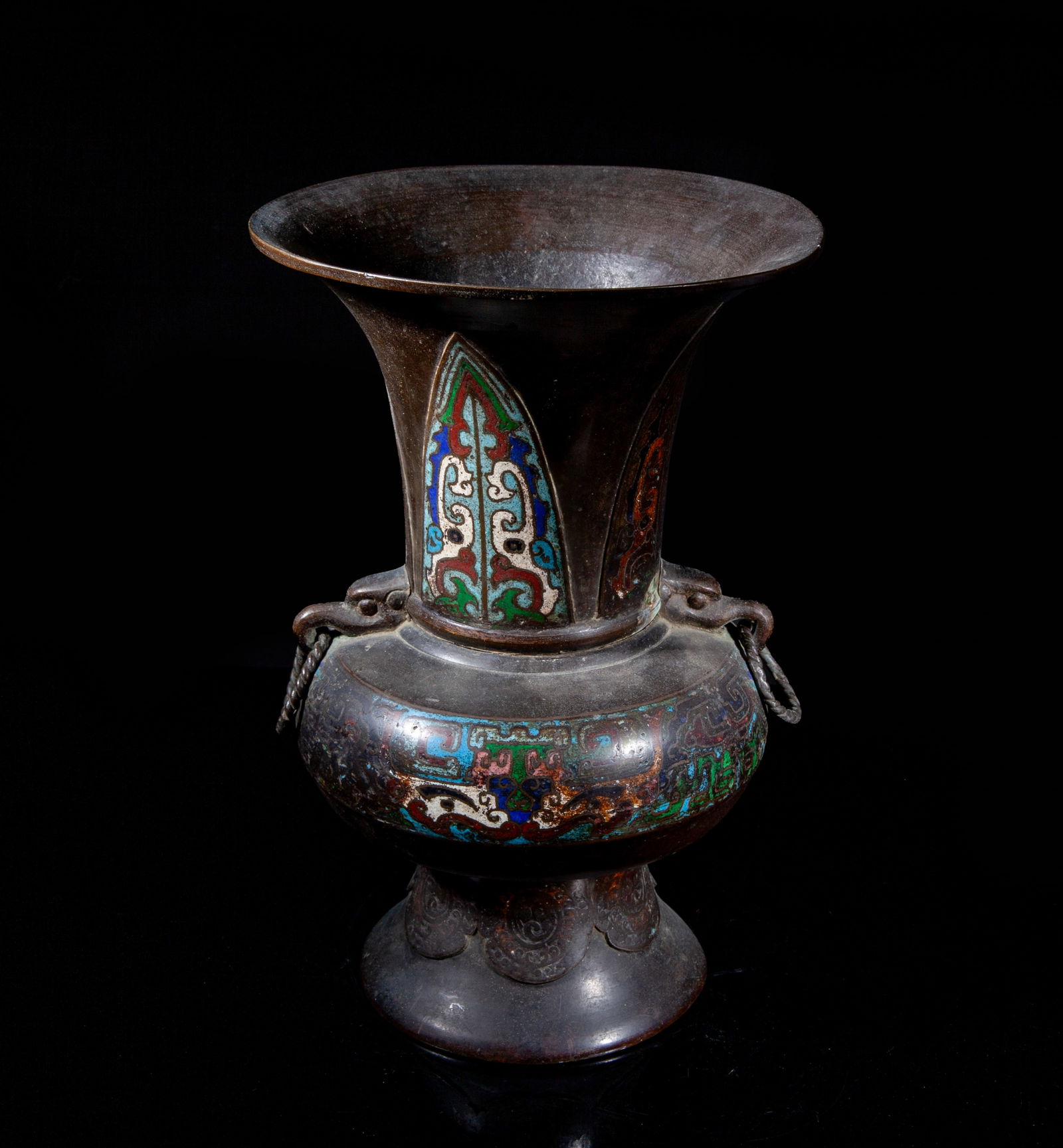 Tall Antique Japanese Cloisonne Vase: The compressed body carved and enameled with archaic motifs, set with two beast mask handles with loops, the spreading neck decorated with upright leaves enclosing stylized beasts, the splayed foot de