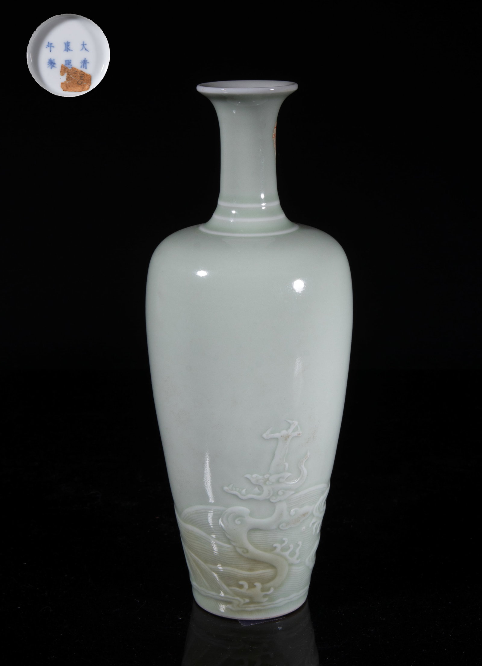 Chinese Green Glazed Porcelain Cabinet Vase: The baluster body rising to a slender neck and a flared rim, the lower body carved in low relief with a dragon throwing itself out of waves, the exterior applied with even pale green glaze, the bottom