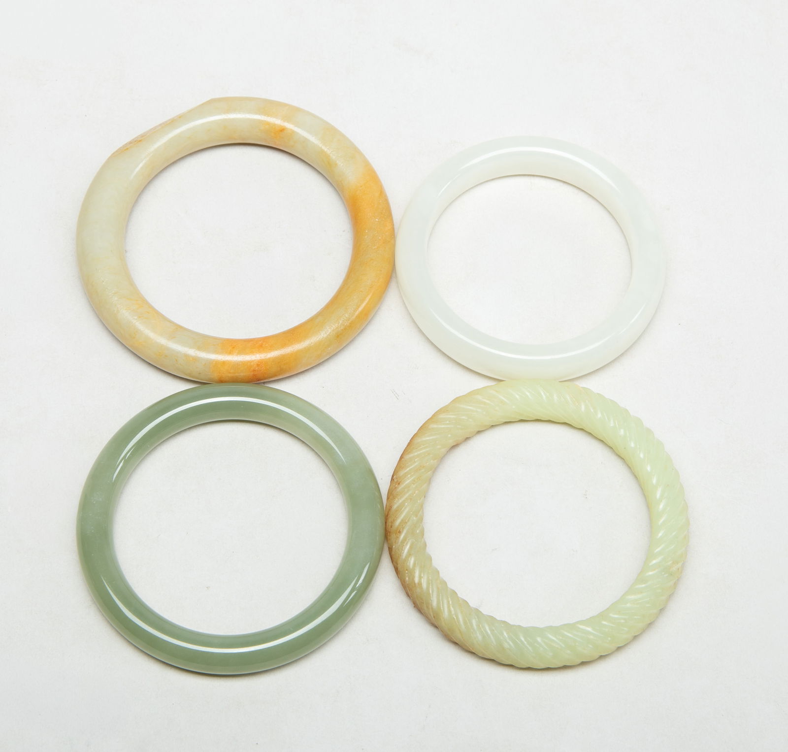 Set Chinese Export Jade Bangles: Set of four Chinese jade carved bangles. Approx. 3.2 inch outer diameter, 2.3 inch inner diameter (largest bangle).