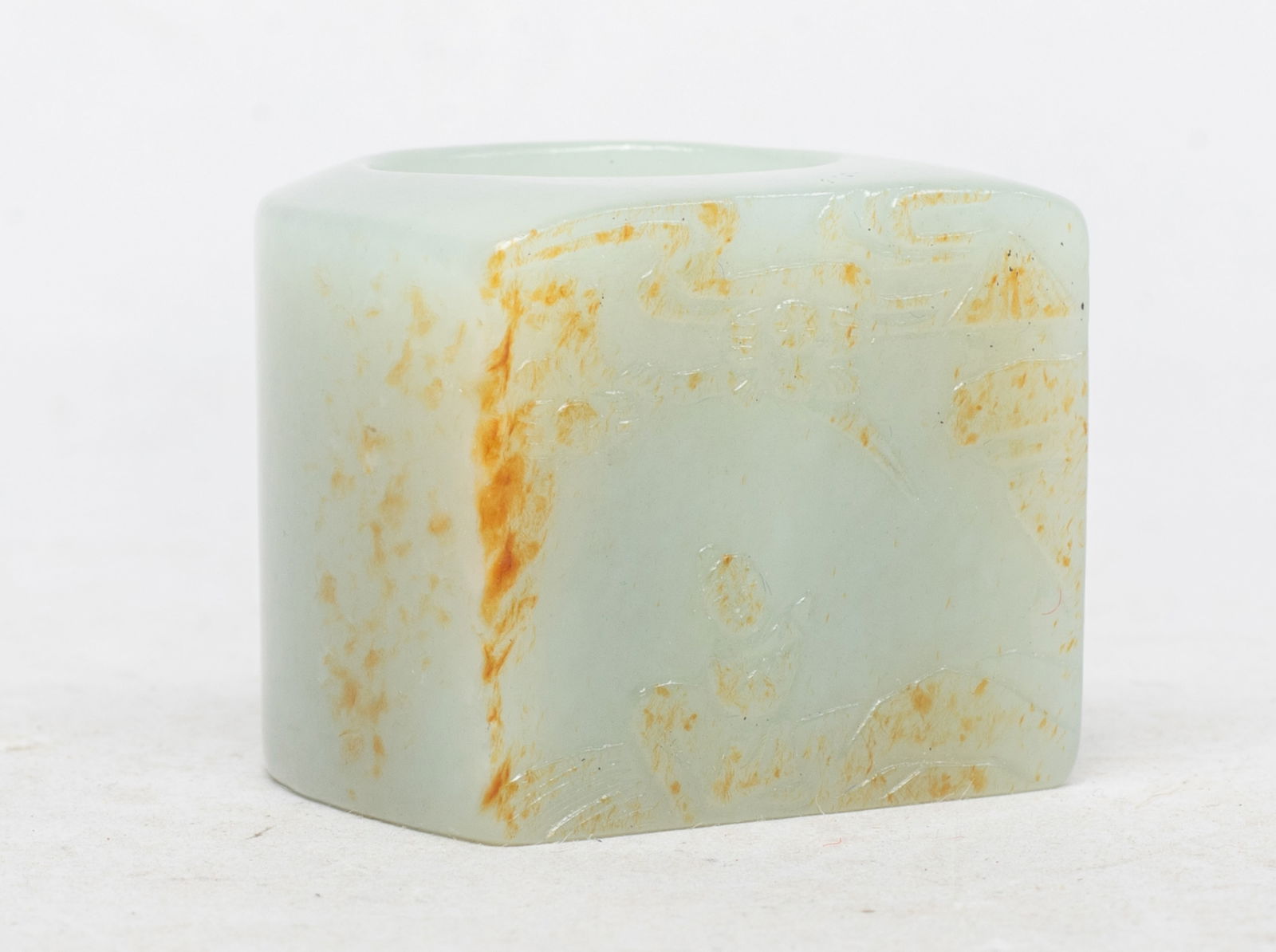 Large Chinese Russet Jade Thumb Ring: Collectible Chinese jade thumb ring, the flat side carved in low relief with a scholar in landscape with pine tree and pavilion, the stone of pale celadon tone with russet inclusions. Approx. 1.36*1.3