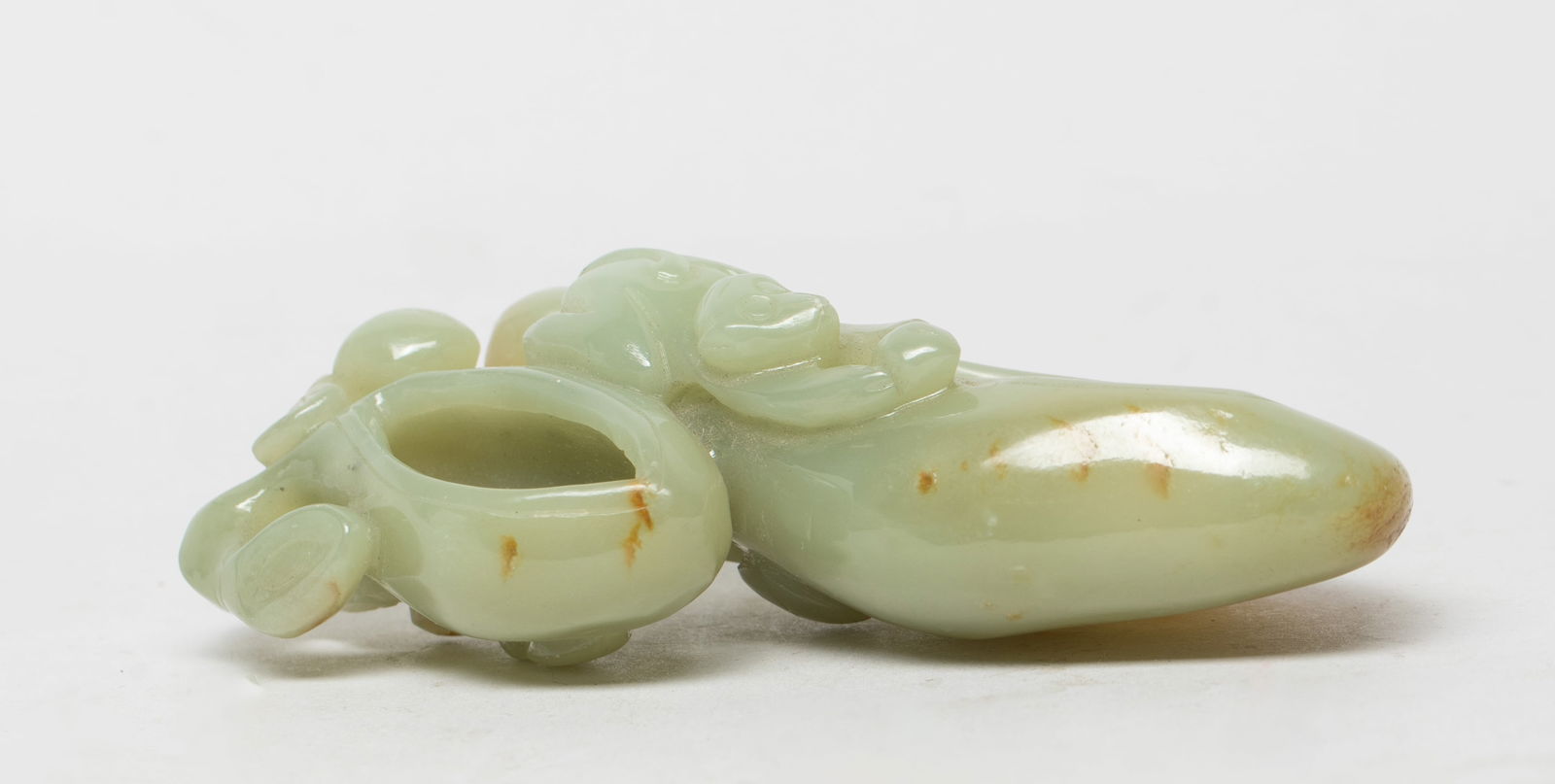 Estate Chinese Russet Jade Washer: Carved as two hollowed peaches surrounded with pierced curling leafy branches bearing smaller peaches, a monkey with recumbent on the side holding a peach, the stone of pale celadon tone with russet i