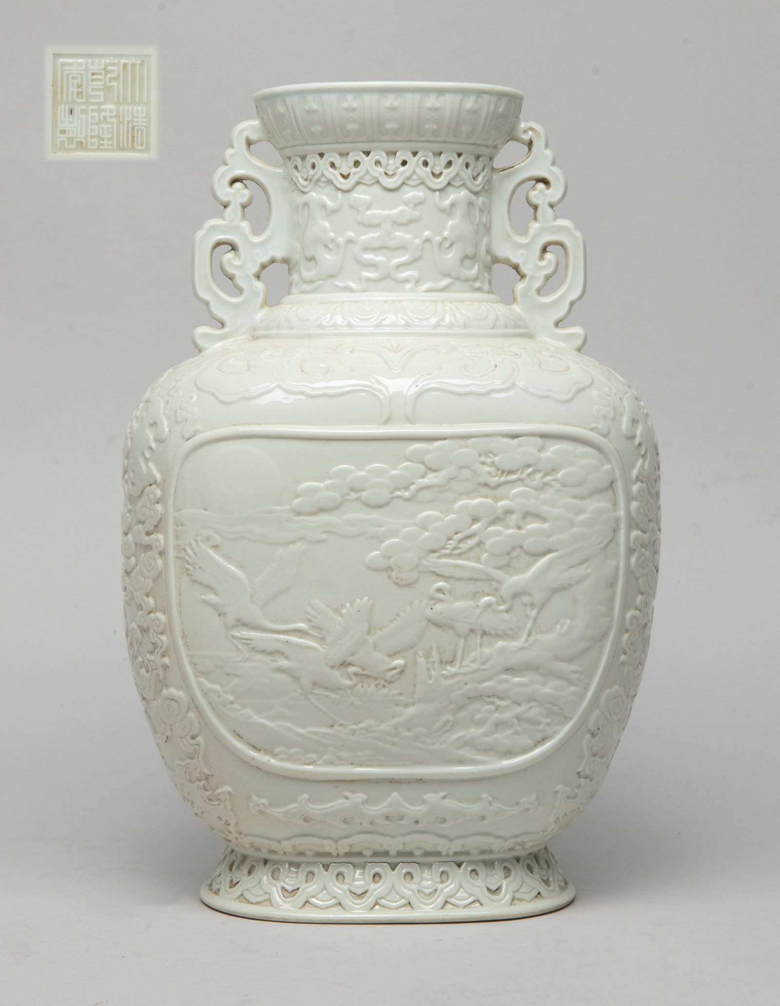 Chinese Detailed Cream White Glazed Porcelain Vase: The vase carved on one side with a panel of cranes and pine tree, the reverse with a panel of magpies and plum blossoms, between bands of ruyi heads and petals, the rest body and the neck carved with 