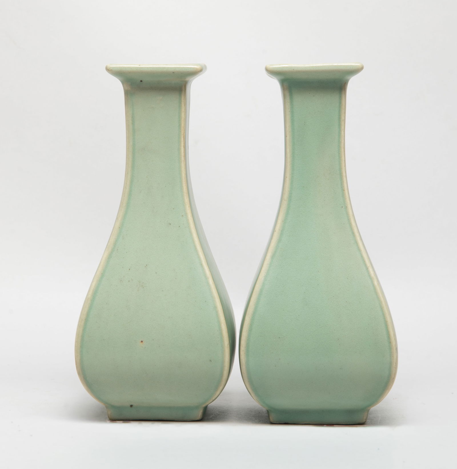 Two Chinese Longquan Porcelain Vases: Each of square section, the pear shaped body rising from a short foot to a slender neck with flared rim, overall covered with mottled celadon glaze. Approx. 7*3.1*3.05 inch (each). The Estate of the S