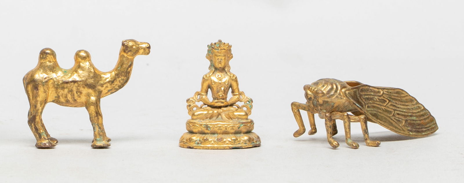 Set Chinese Gilt Bronze Toggles: Three Chinese gilt bronze toggles, one cast of cicada form, one of camel form, the other cast as Buddha seated on a waisted lotus base, the hands holding an implement. Approx. 1.8*1*0.7 inch (cicada s
