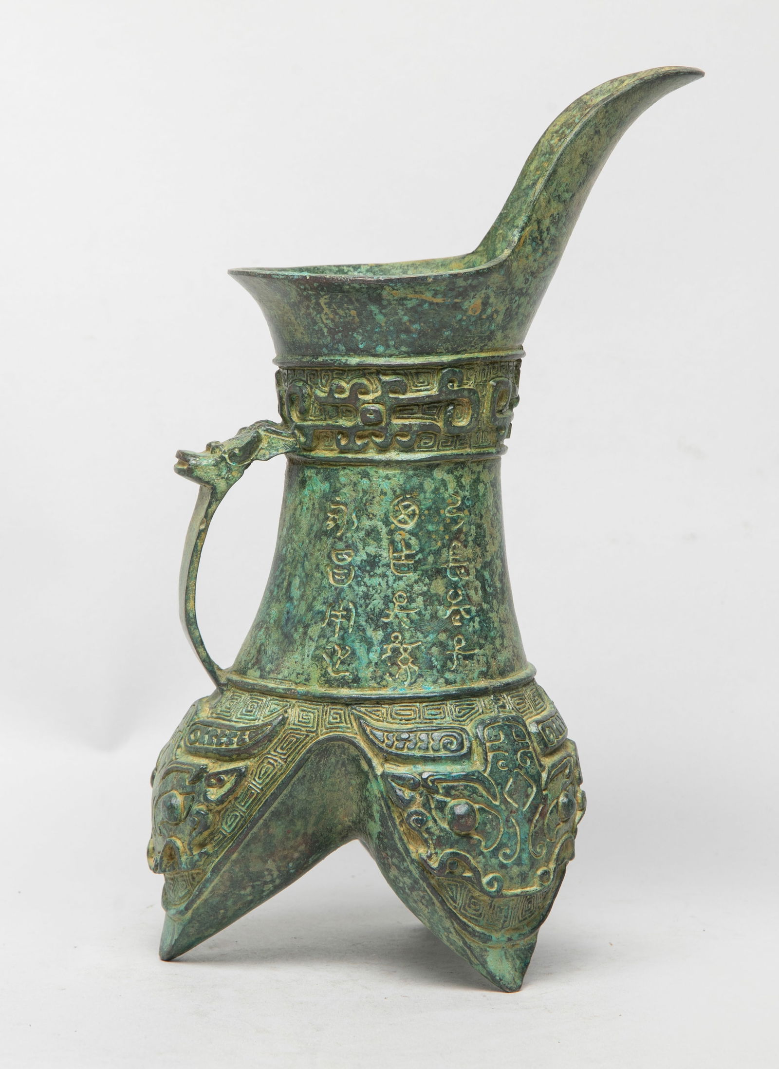 Chinese Export Bronze Vase: The body supported by three pointy triangular feet, the tall straight neck rising to a tall flaring mouth, finely cast with three sets of large taotie masks on the feet, and a band of archaic beasts o